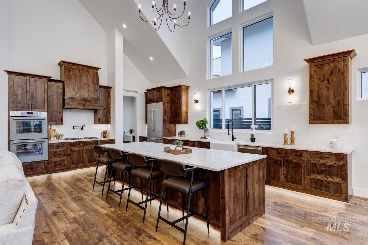 Kitchen with decorative backsplash, stainless steel appliances, dark brown cabinetry, a large island, and a high ceiling