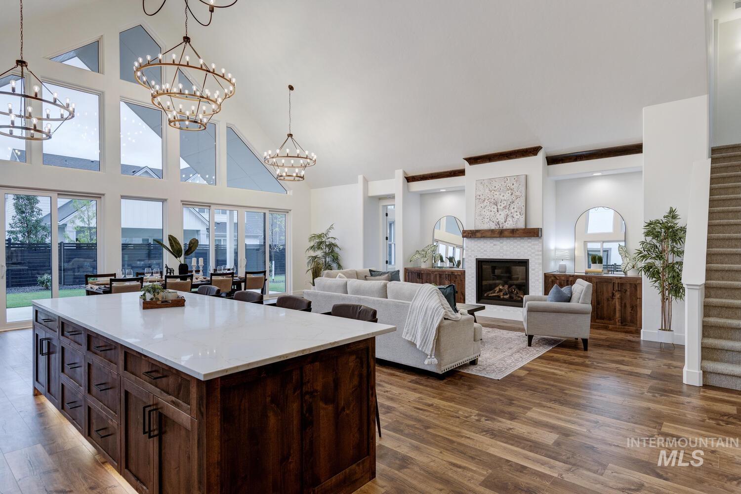 Kitchen with dark brown cabinets, a glass covered fireplace, high vaulted ceiling, open floor plan, and decorative light fixtures