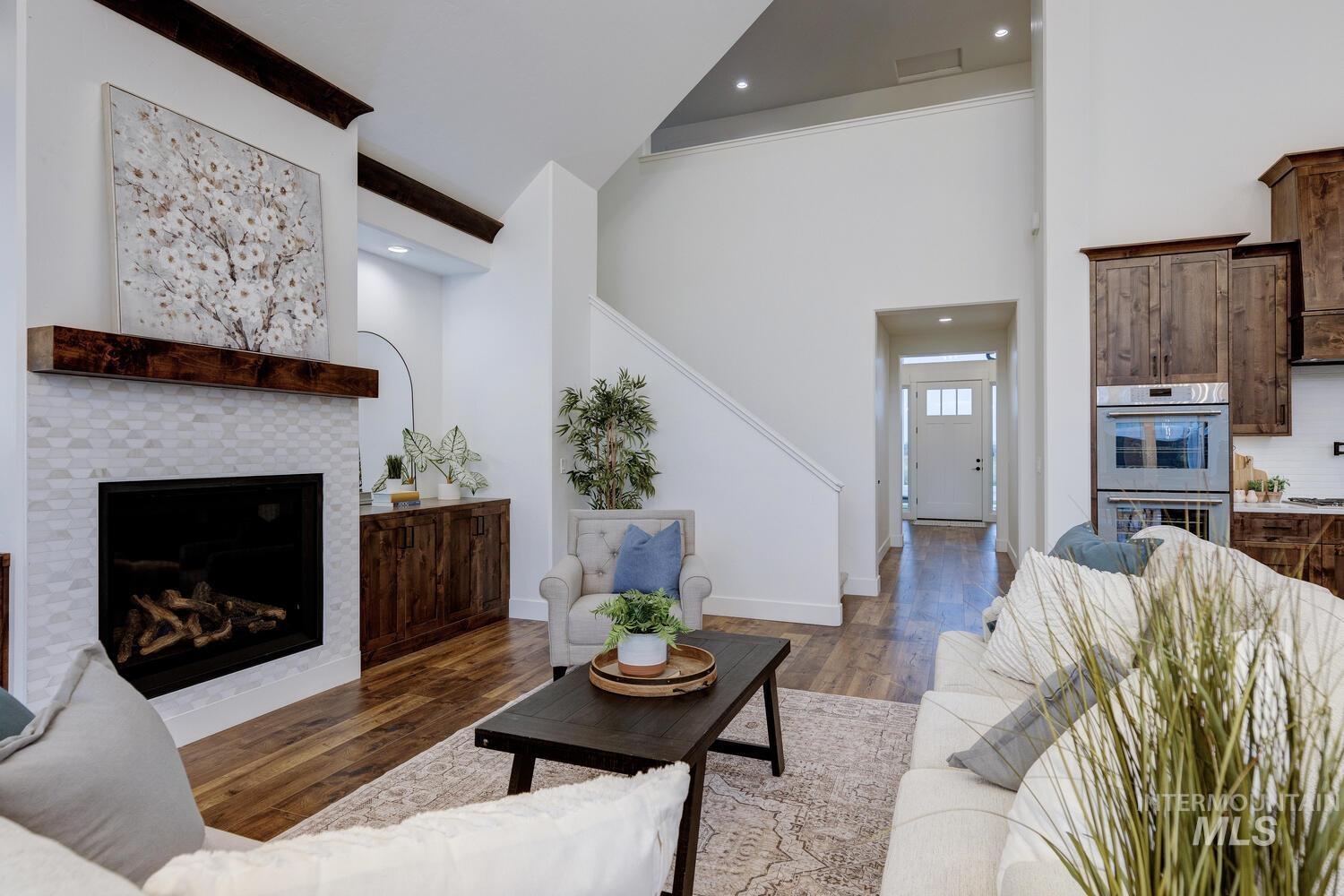Living room with dark wood finished floors, a fireplace, a high ceiling, and recessed lighting