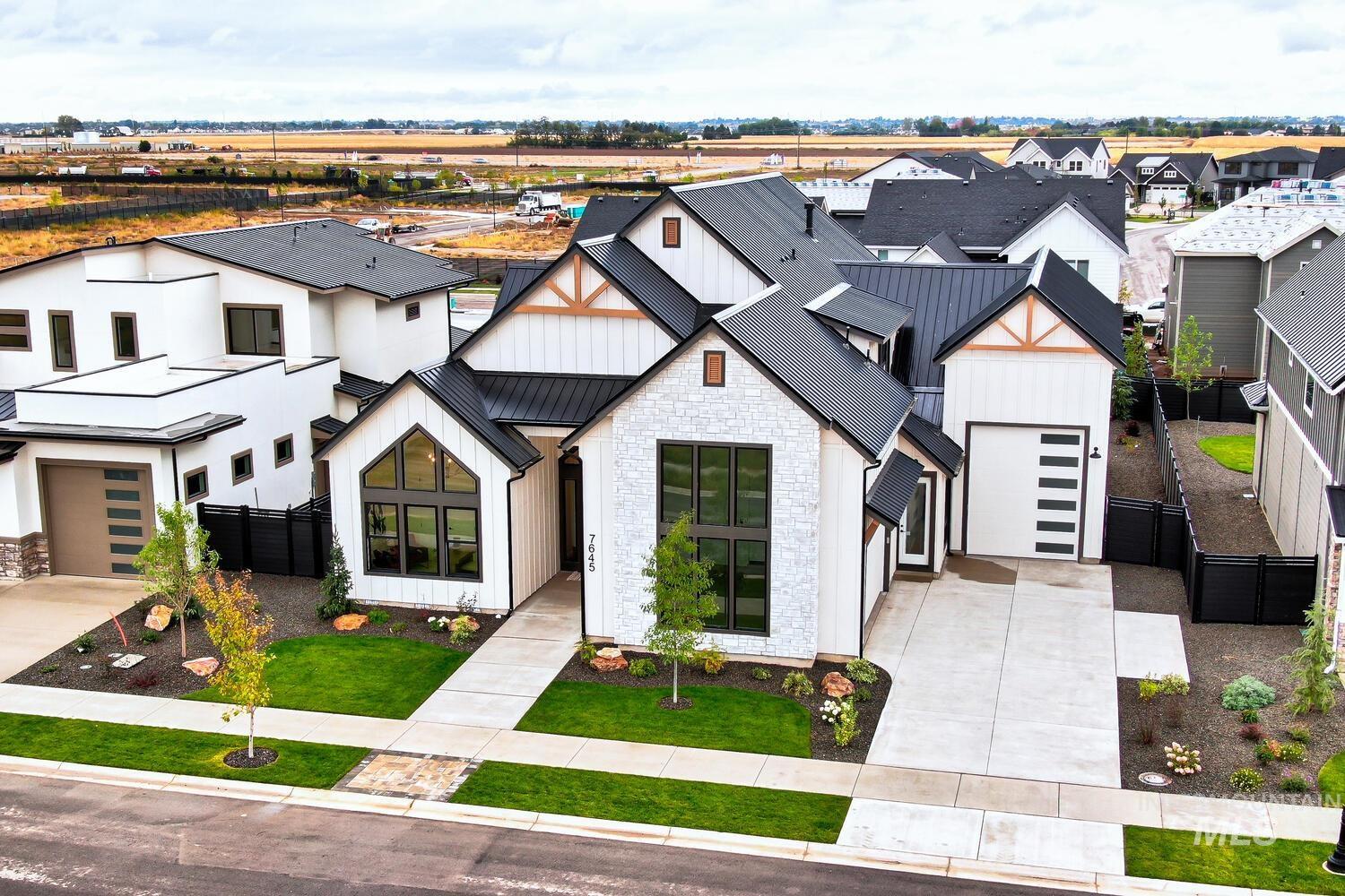 Modern farmhouse style home with a residential view, concrete driveway, a metal roof, and board and batten siding