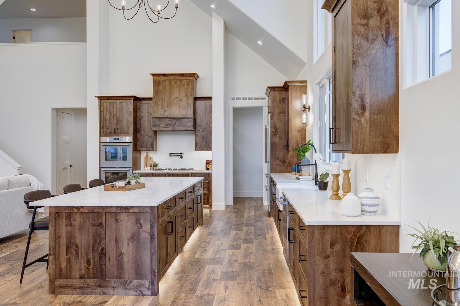 Kitchen with backsplash, a kitchen bar, high vaulted ceiling, healthy amount of natural light, and light stone counters