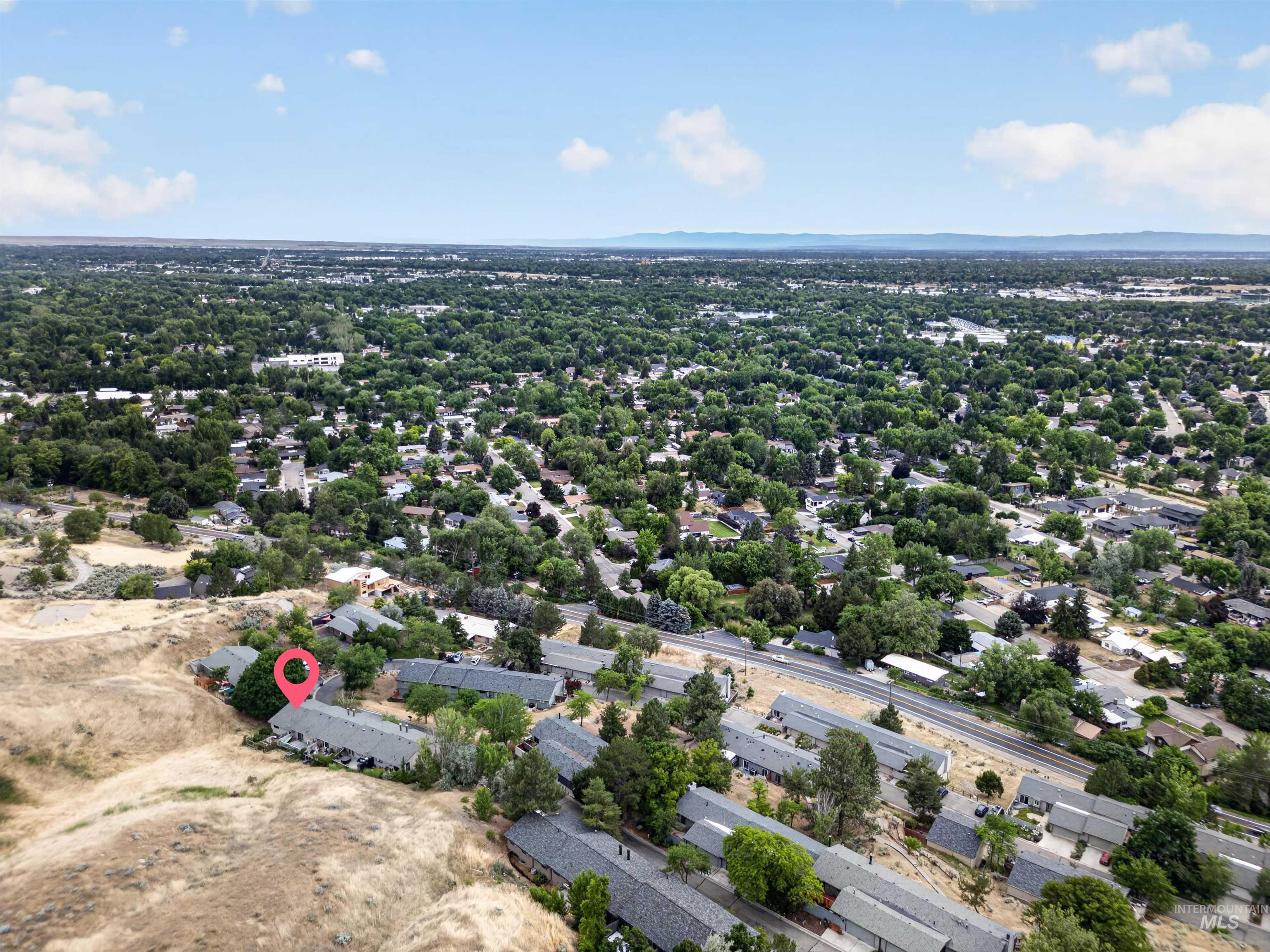 Aerial perspective highlighting a tree-lined residential area with a prominent pinpoint marker indicating a specific property