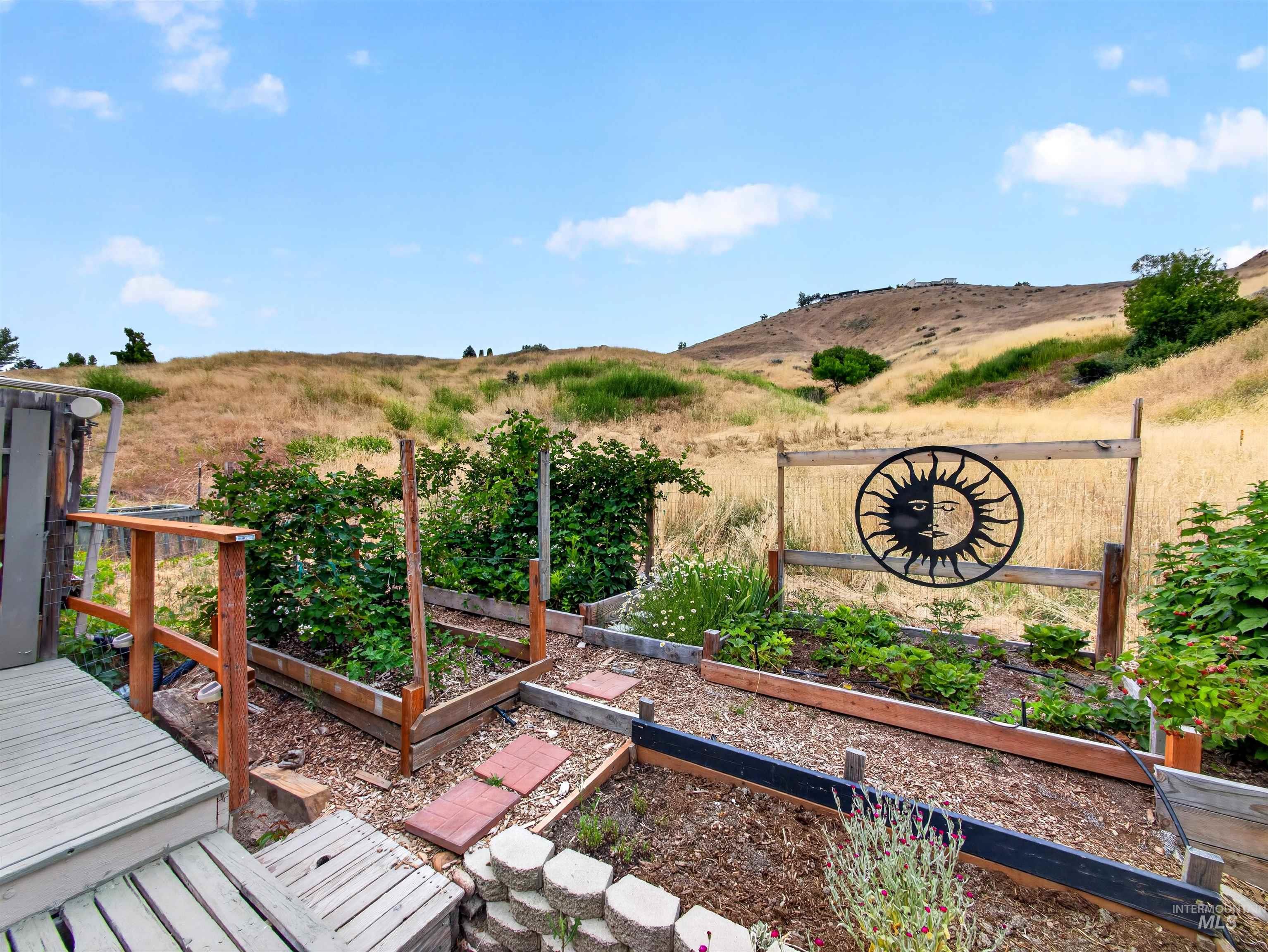 Terraced garden beds featuring established plantings and decorative metalwork, set against a natural hillside backdrop