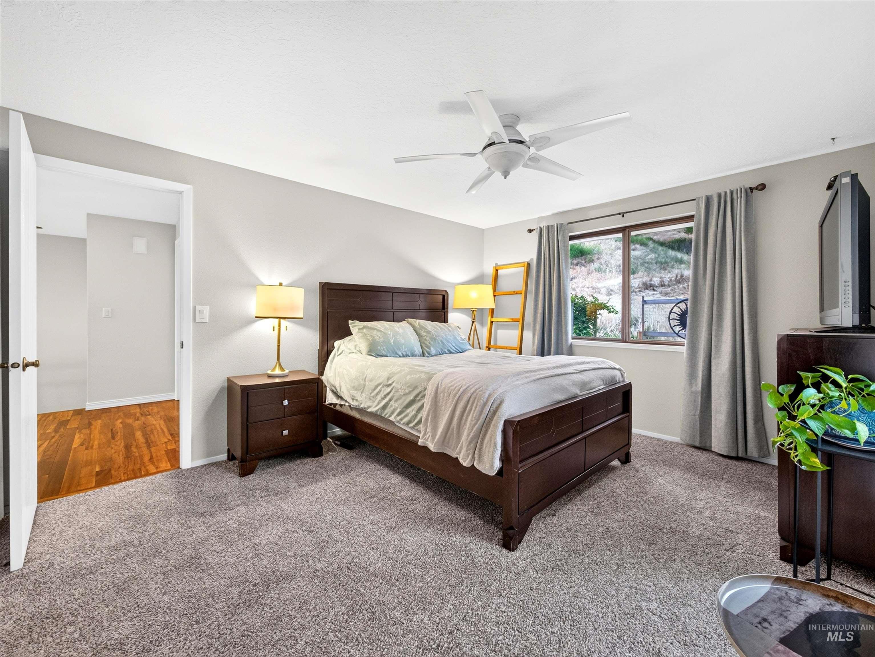 Spacious room featuring neutral carpeting, a large window, and a ceiling fan