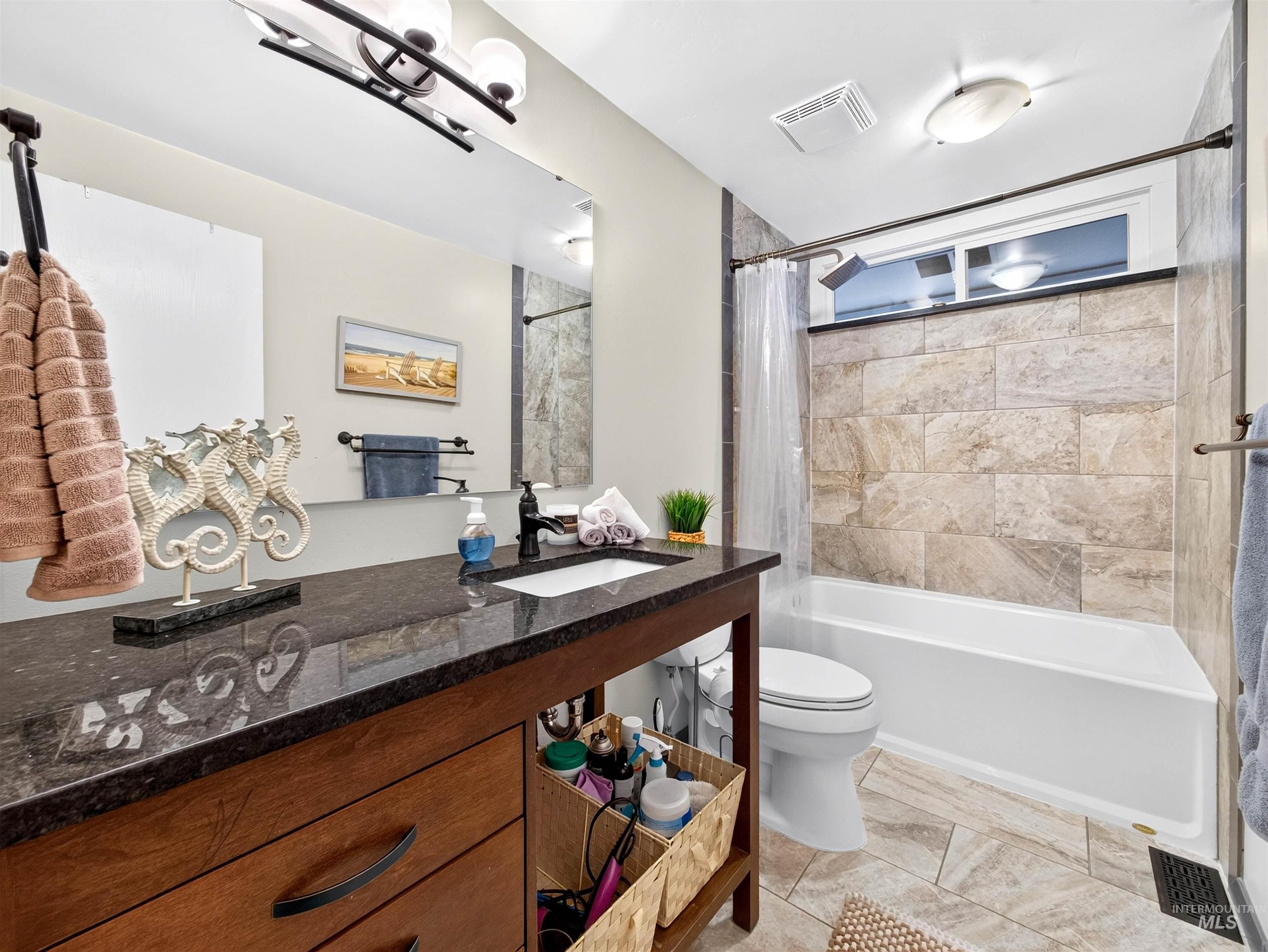 Bathroom featuring a wood-finish vanity with a dark countertop and undermount sink