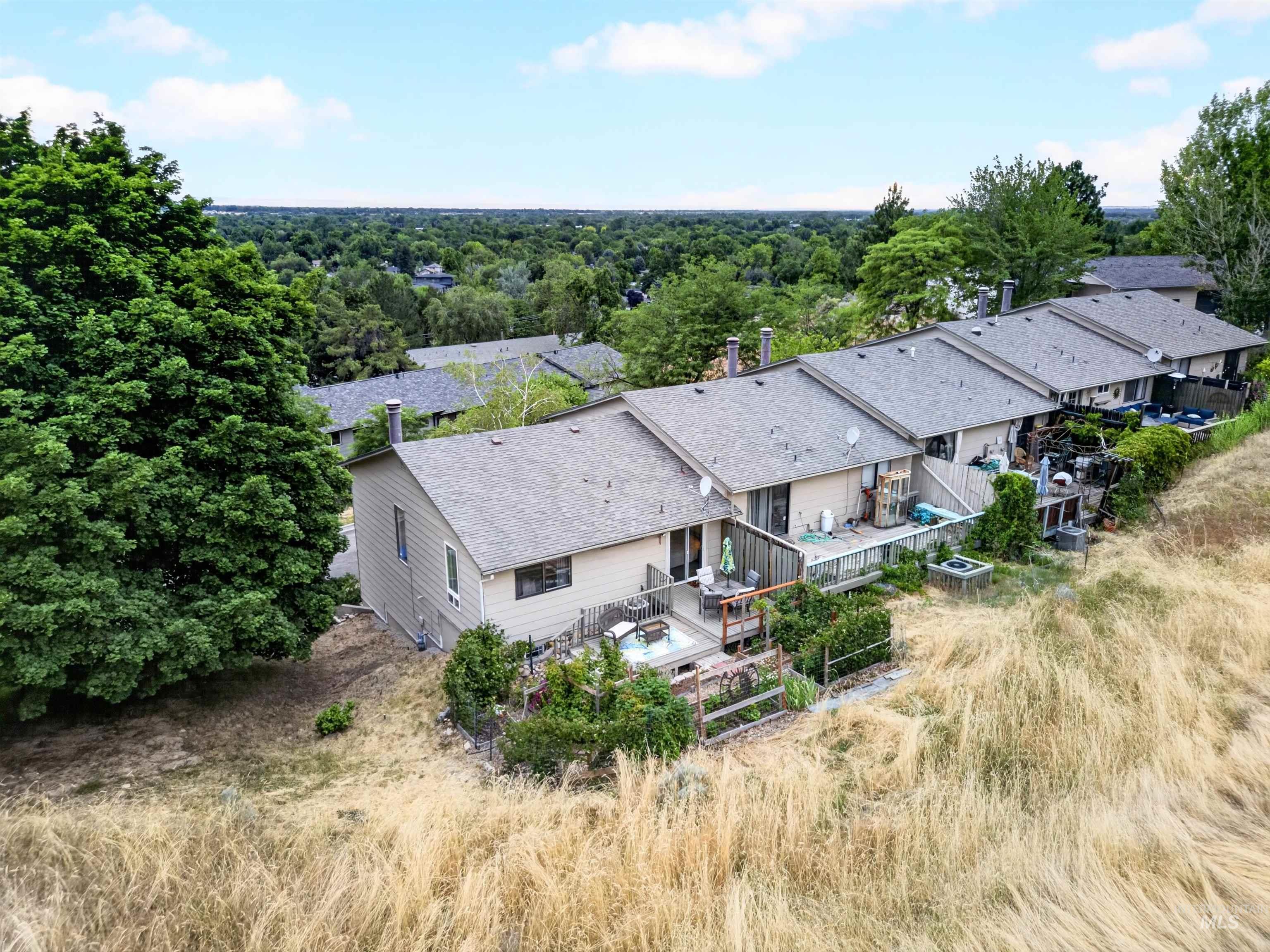 Rear property exterior featuring a multi-level deck, built-in hot tub, and lush surrounding greenery