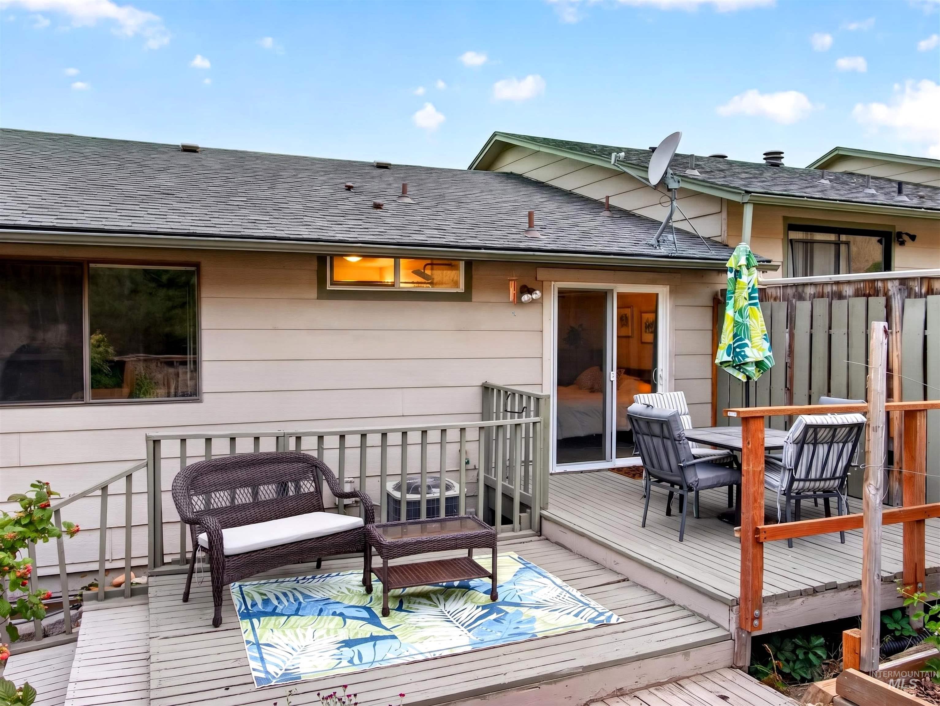 Outdoor wood deck featuring a sliding glass door entry, wood siding, and shingle roofing