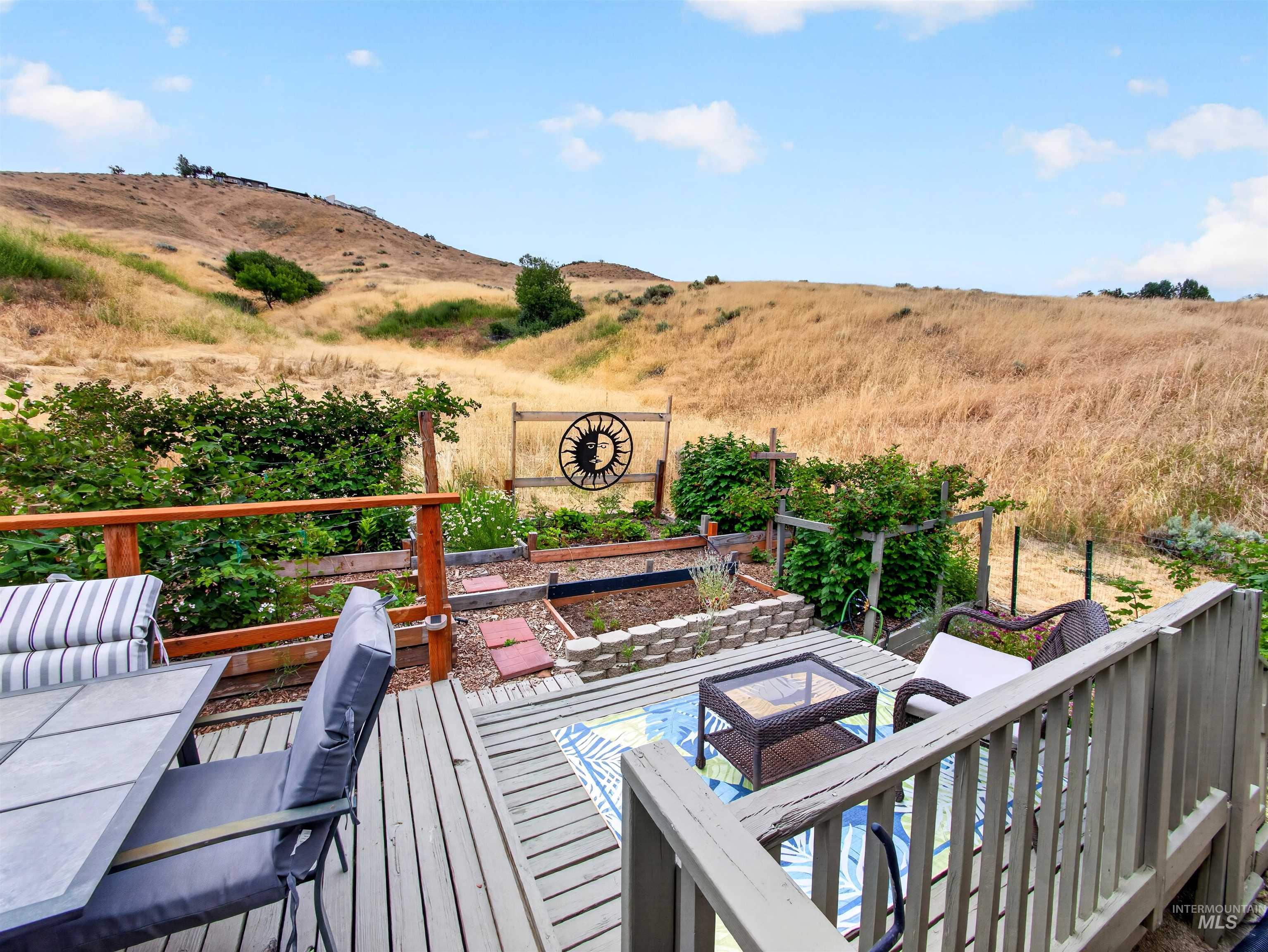 Outdoor deck with wood-finish railing, overlooking a terraced garden area with raised beds