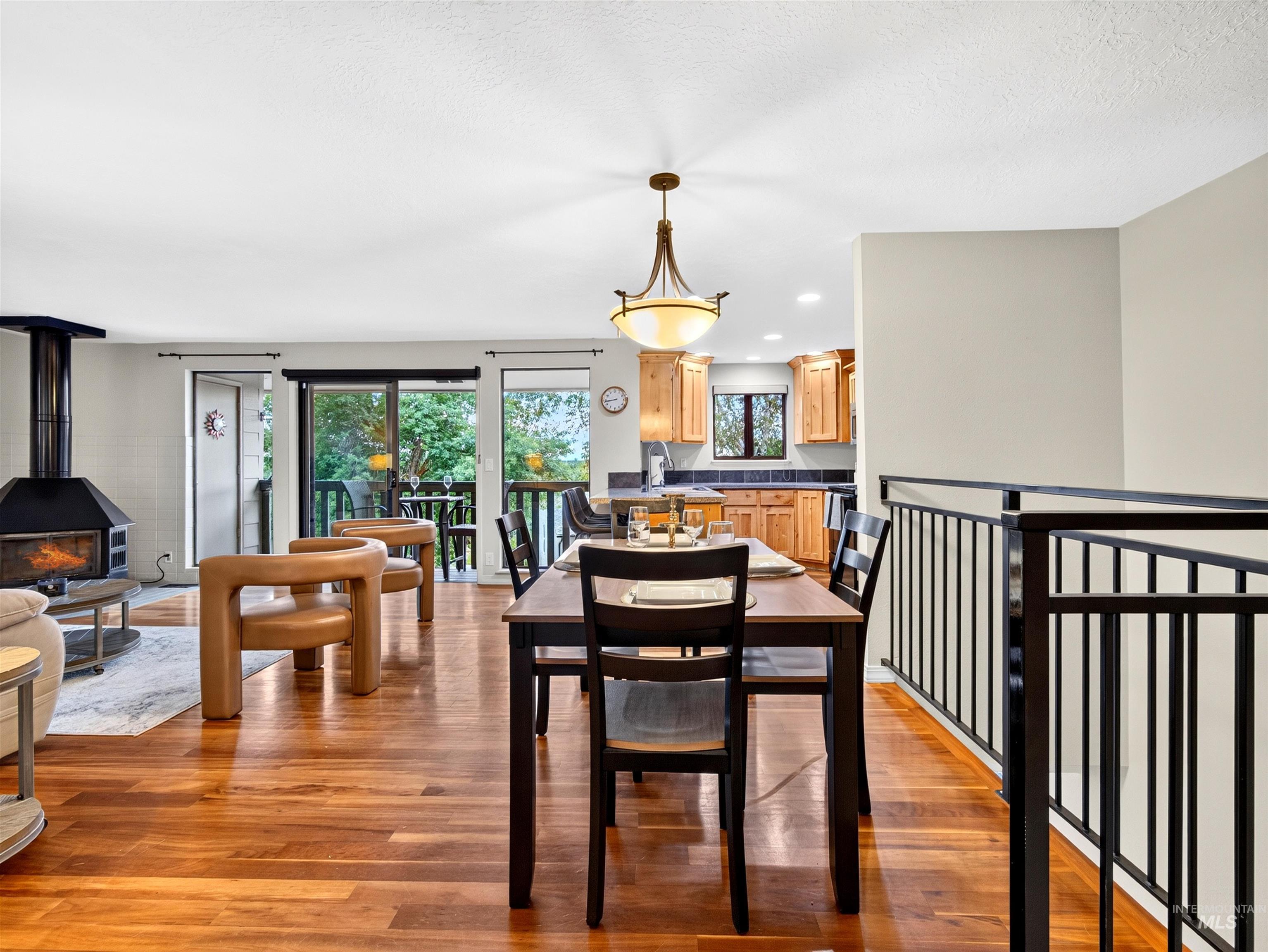 Open-concept living area featuring wood-finish flooring, a built-in fireplace, and a dining area with an overhead chandelier