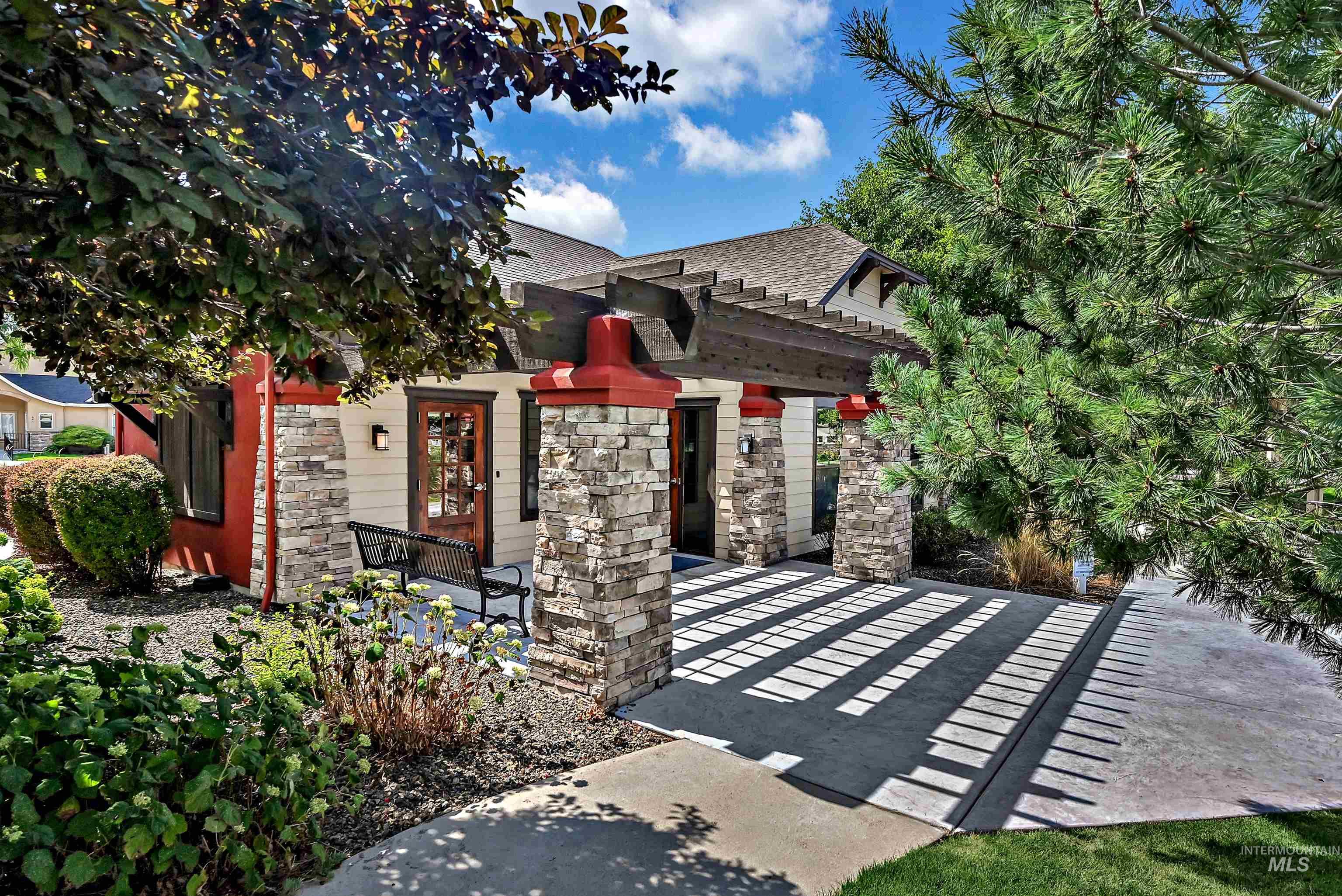 View of front of property featuring stone siding, a patio area, a shingled roof, and a pergola