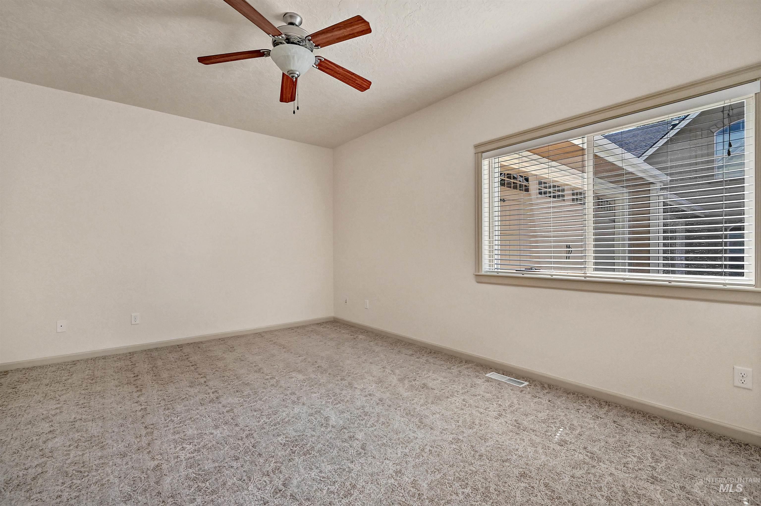 Carpeted spare room with ceiling fan and a textured ceiling