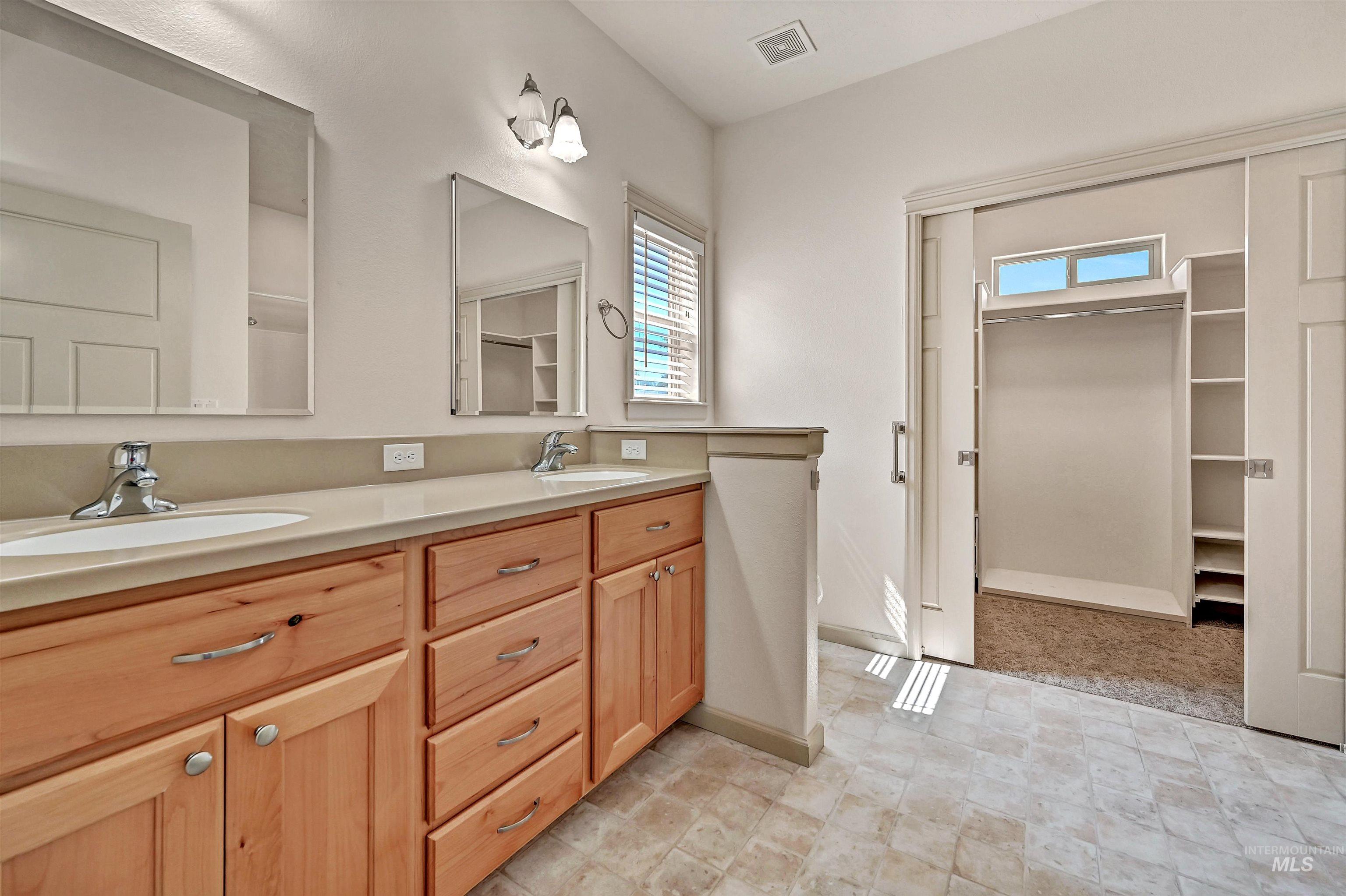 Bathroom with a walk in closet and double vanity