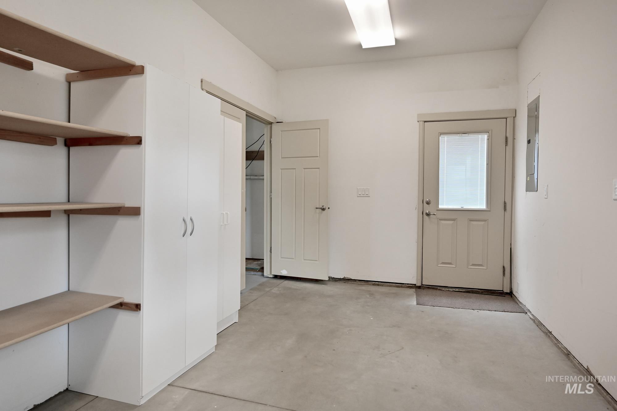 Corridor featuring unfinished concrete flooring and electric panel