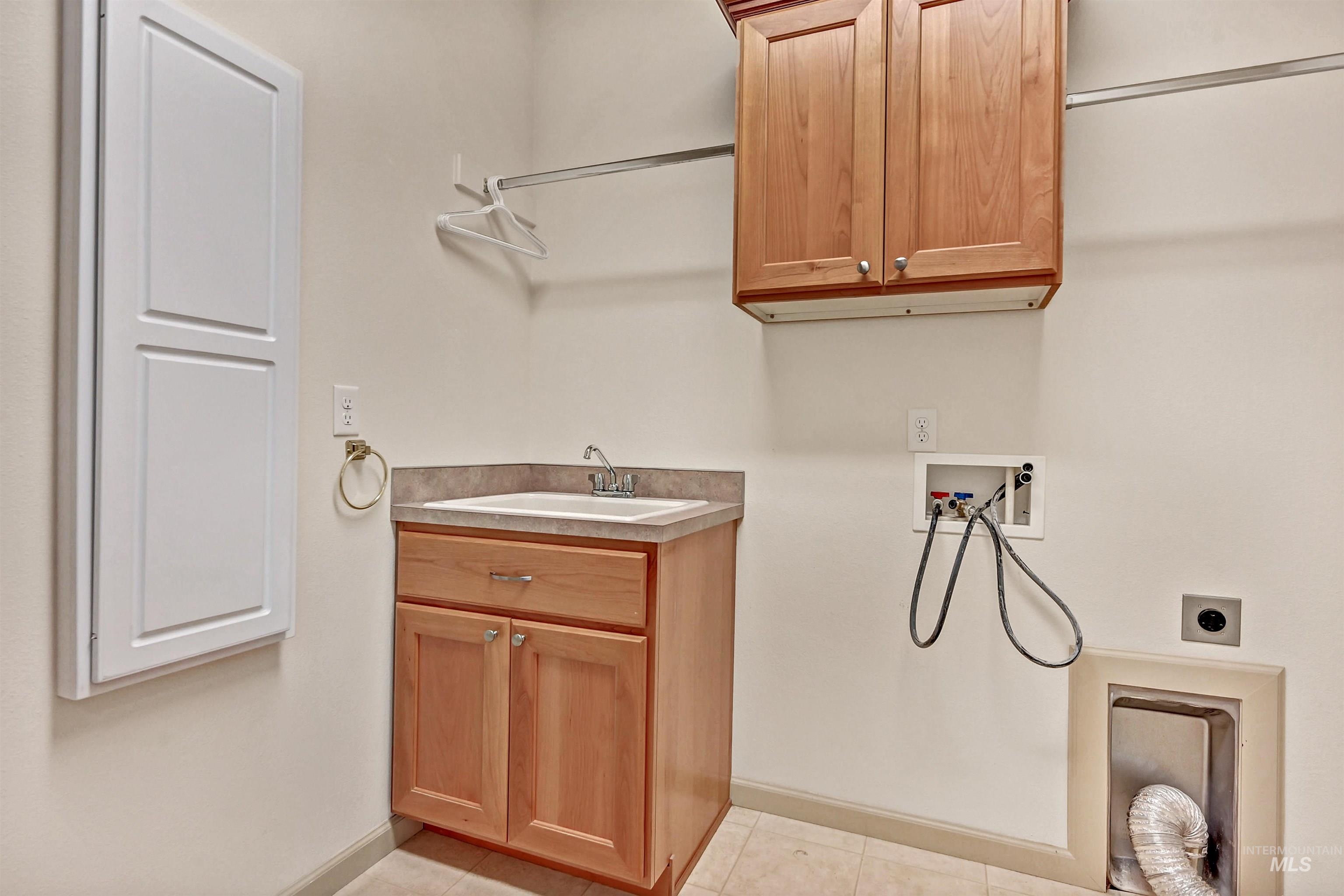 Laundry room featuring cabinet space, light tile patterned floors, hookup for a washing machine, and hookup for an electric dryer