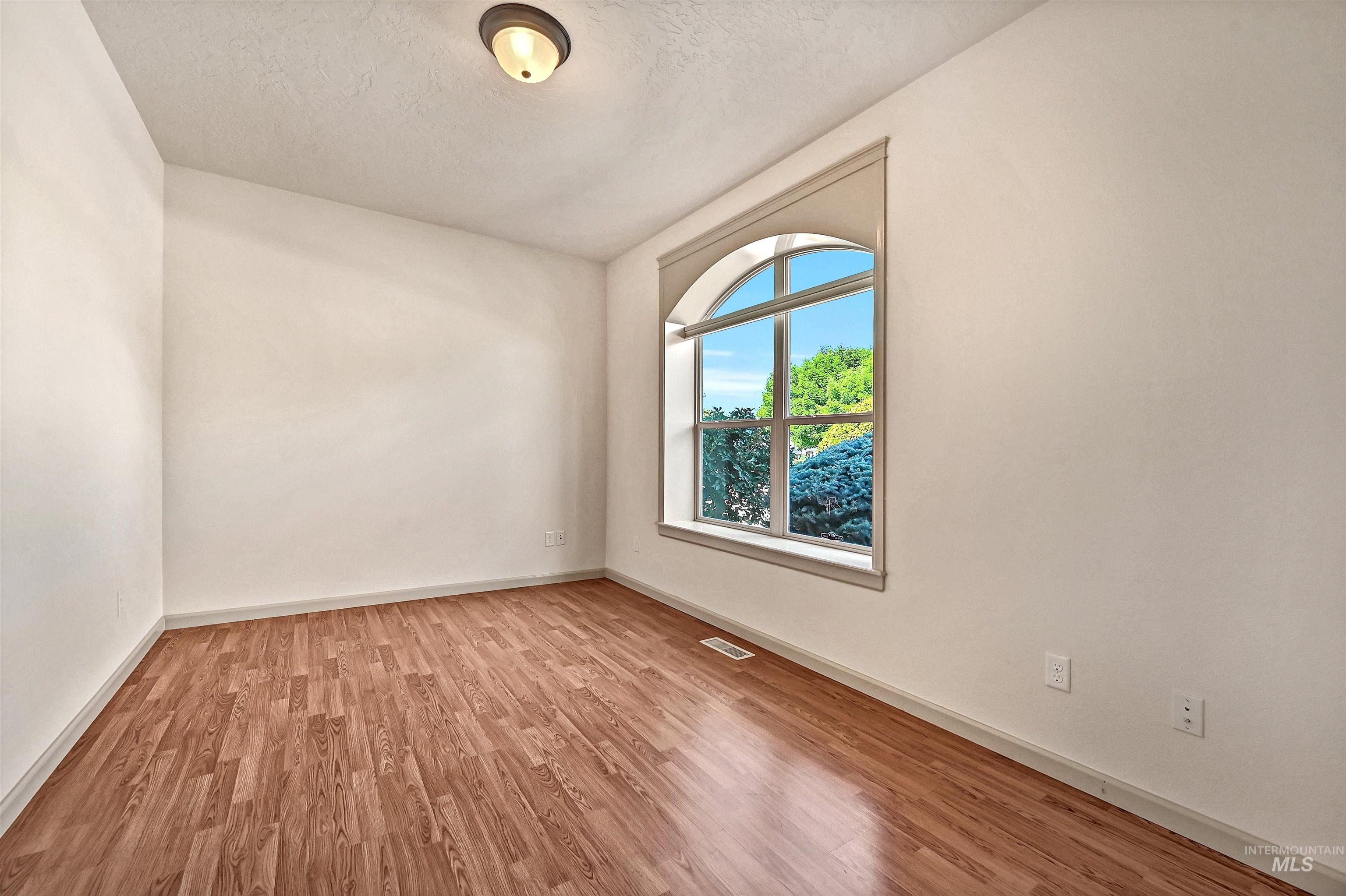 Unfurnished room featuring light wood-style flooring and a textured ceiling