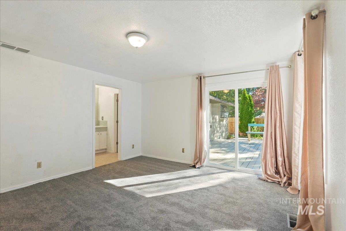 Unfurnished bedroom featuring access to exterior, carpet floors, a textured ceiling, and ensuite bathroom