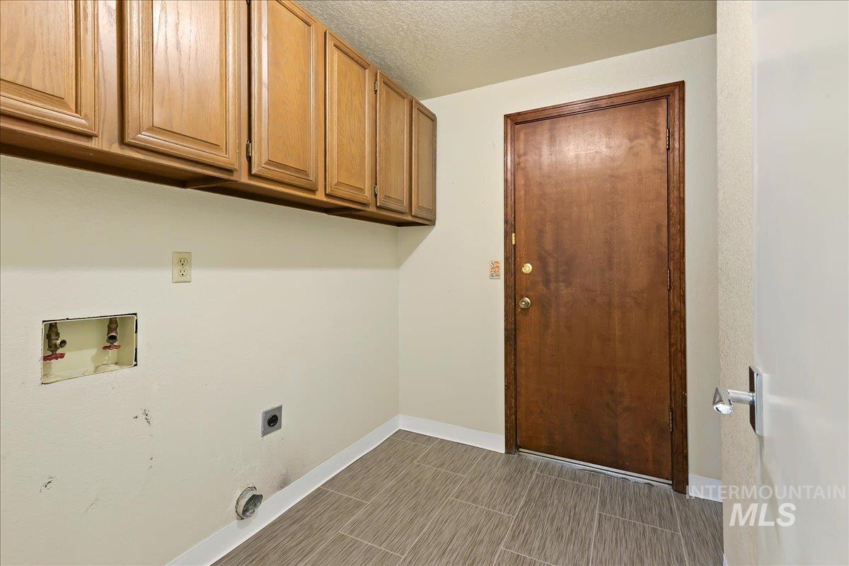 Laundry area featuring a textured ceiling, washer hookup, electric dryer hookup, and cabinet space