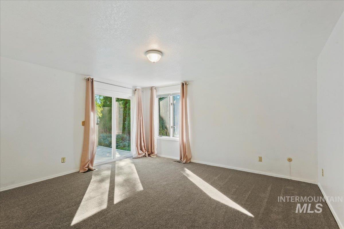 Empty room featuring dark colored carpet and a textured ceiling