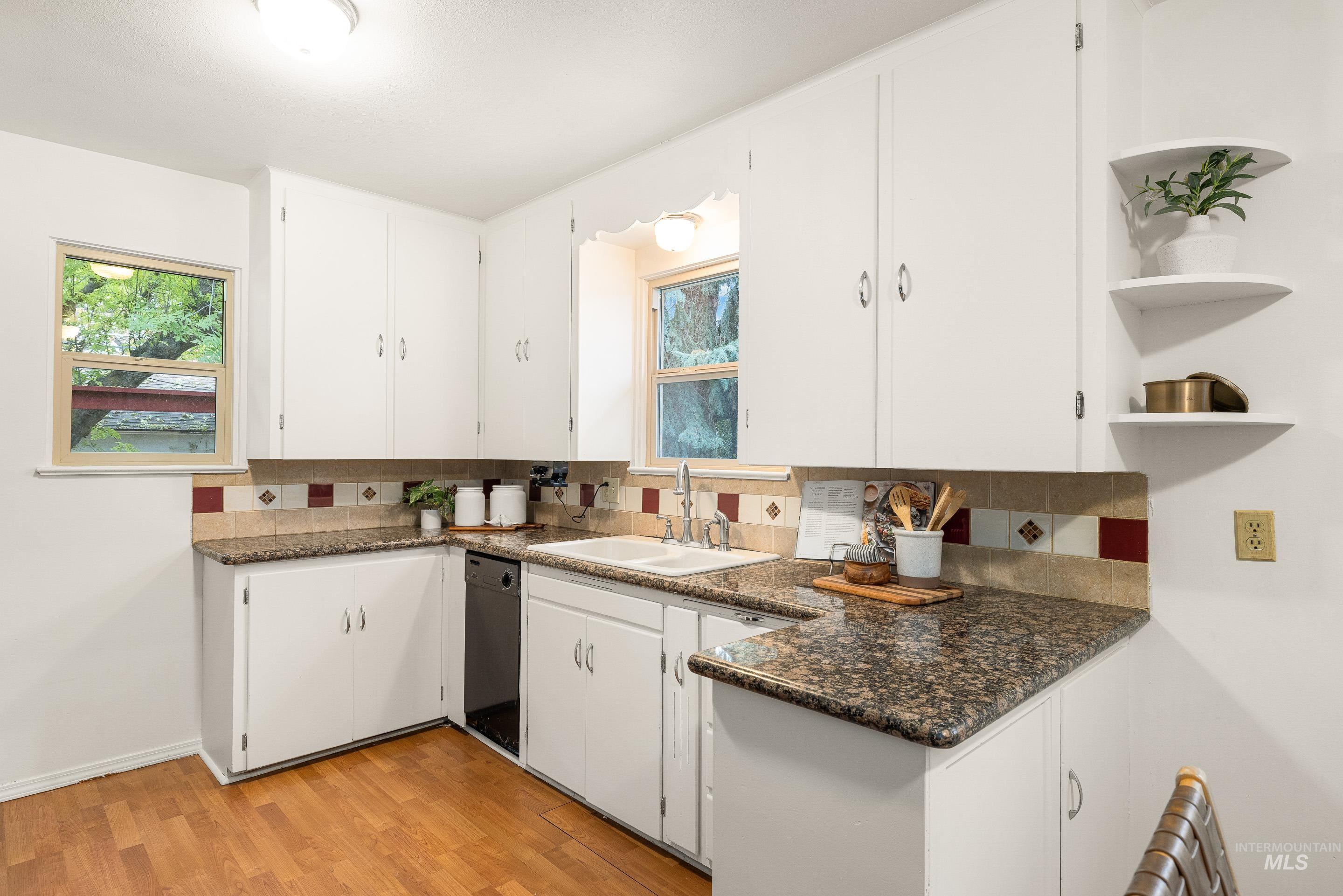 Kitchen featuring open shelves, white cabinets, light wood-type flooring, and decorative backsplash