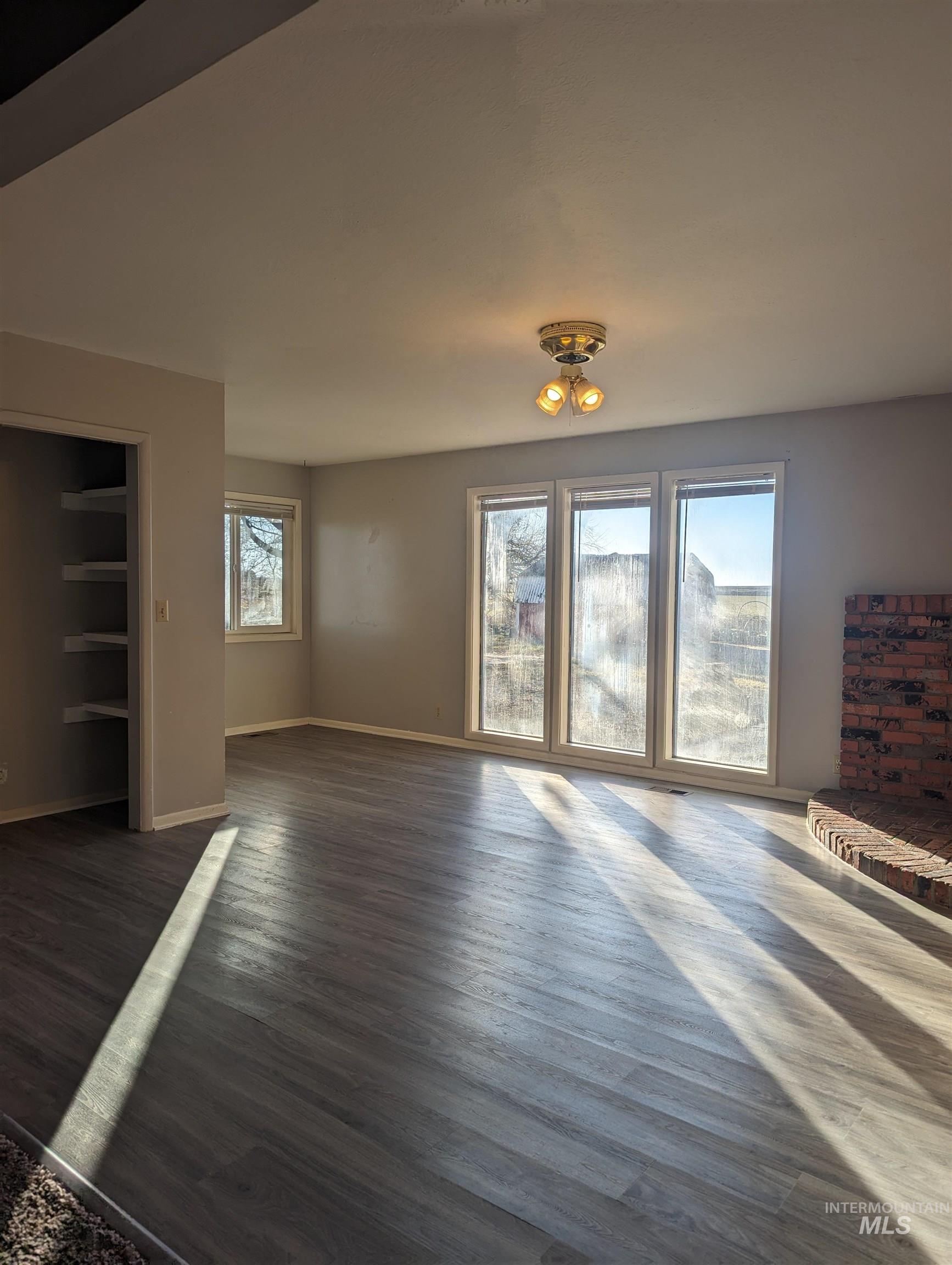 Unfurnished living room with dark wood finished floors and baseboards
