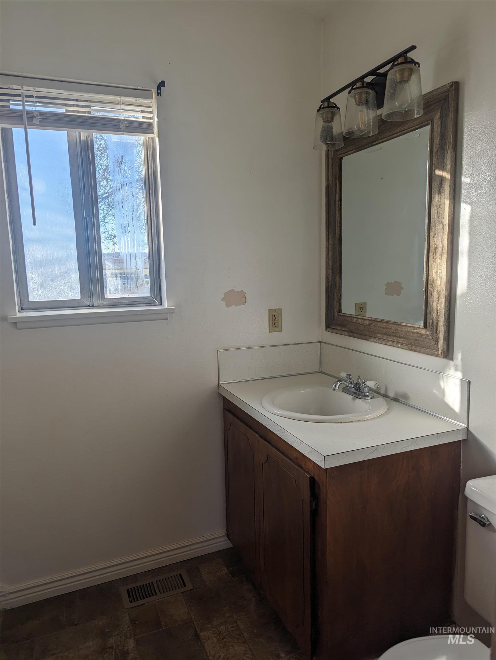 Bathroom featuring vanity and dark stone finish flooring
