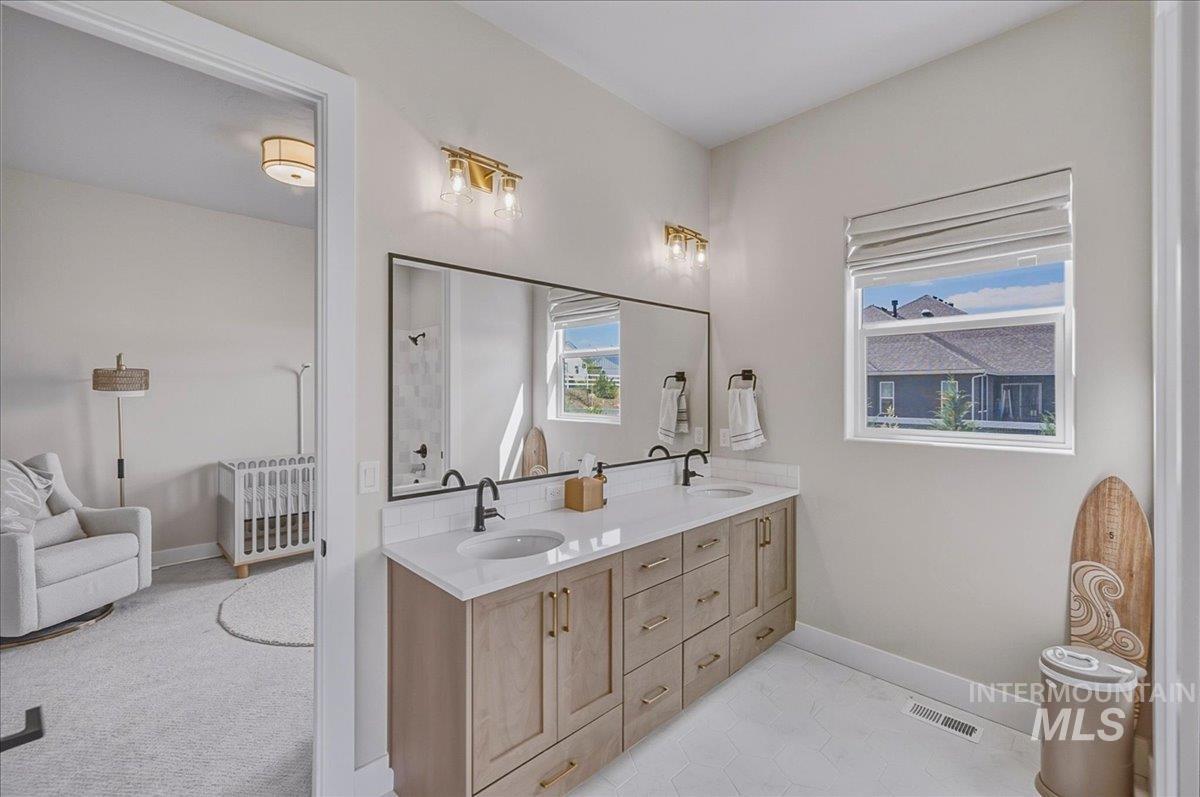 Double vanity featuring light wood-finish cabinetry, white countertops, and matte black fixtures