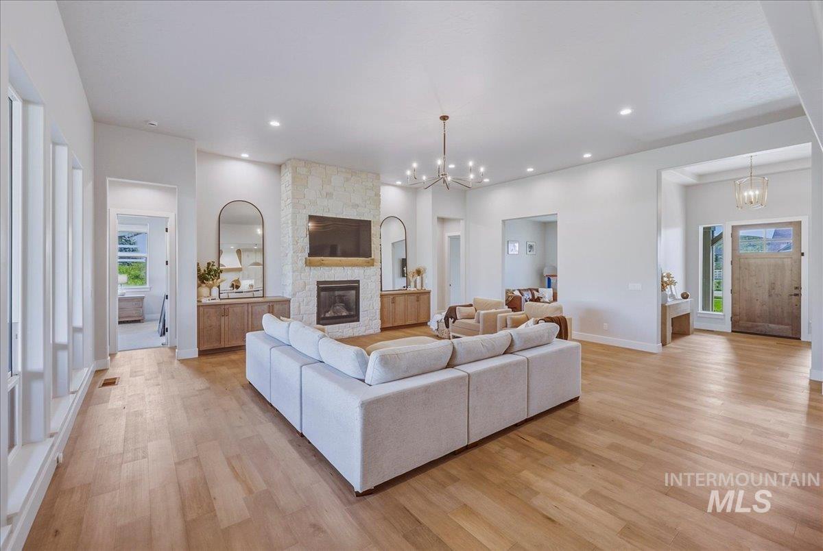 Spacious living area featuring light wood-finish flooring, a stone-clad fireplace with a wood mantle, and built-in cabinetry