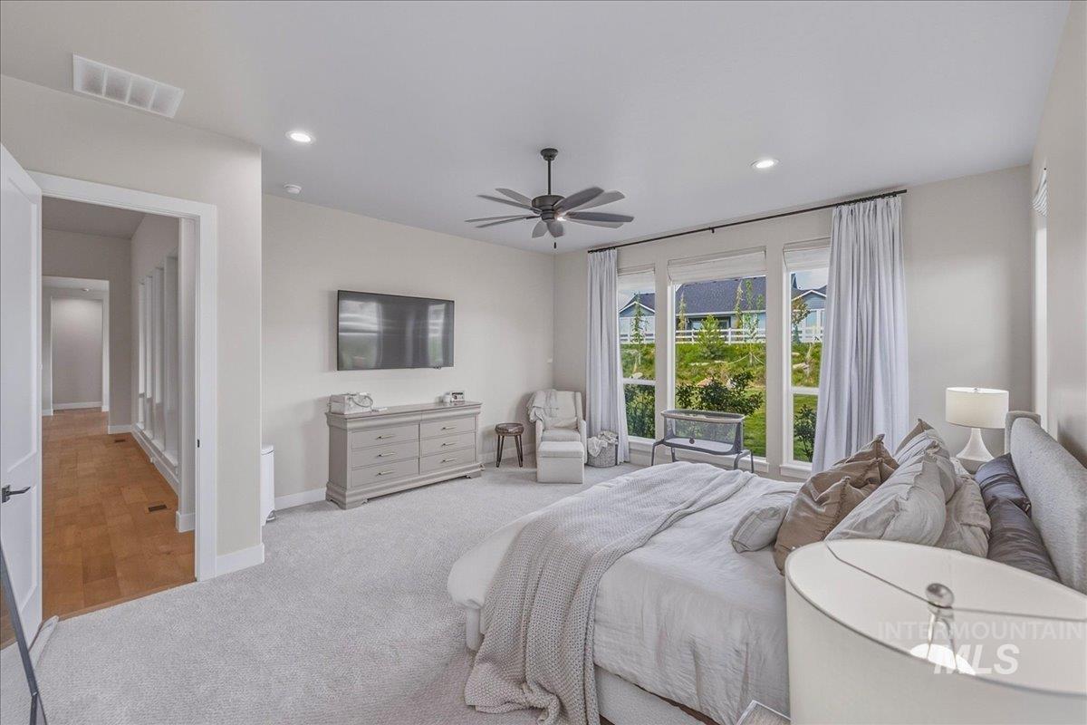 Carpeted bedroom featuring a ceiling fan with integrated lighting, recessed lighting, and large windows with white trim
