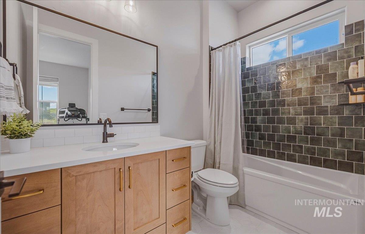 Bathroom featuring a natural wood-finish vanity with gold-tone hardware, a white countertop, and a large framed mirror