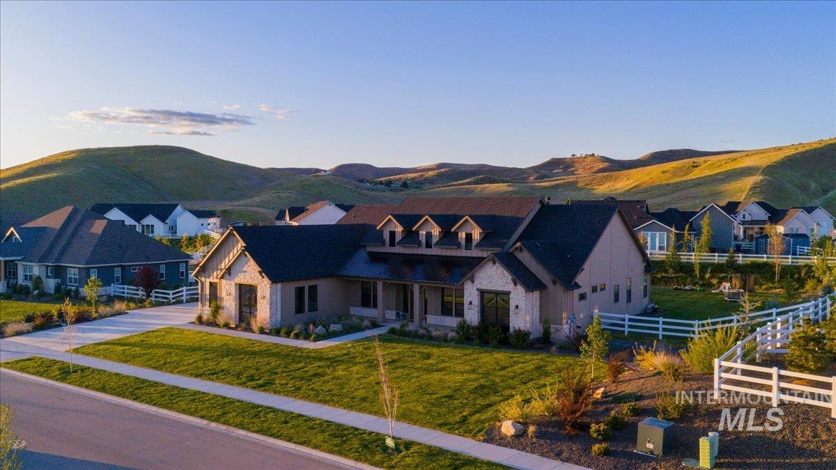 Spacious property featuring a stone and siding exterior, dark shingle roof, and a covered front porch