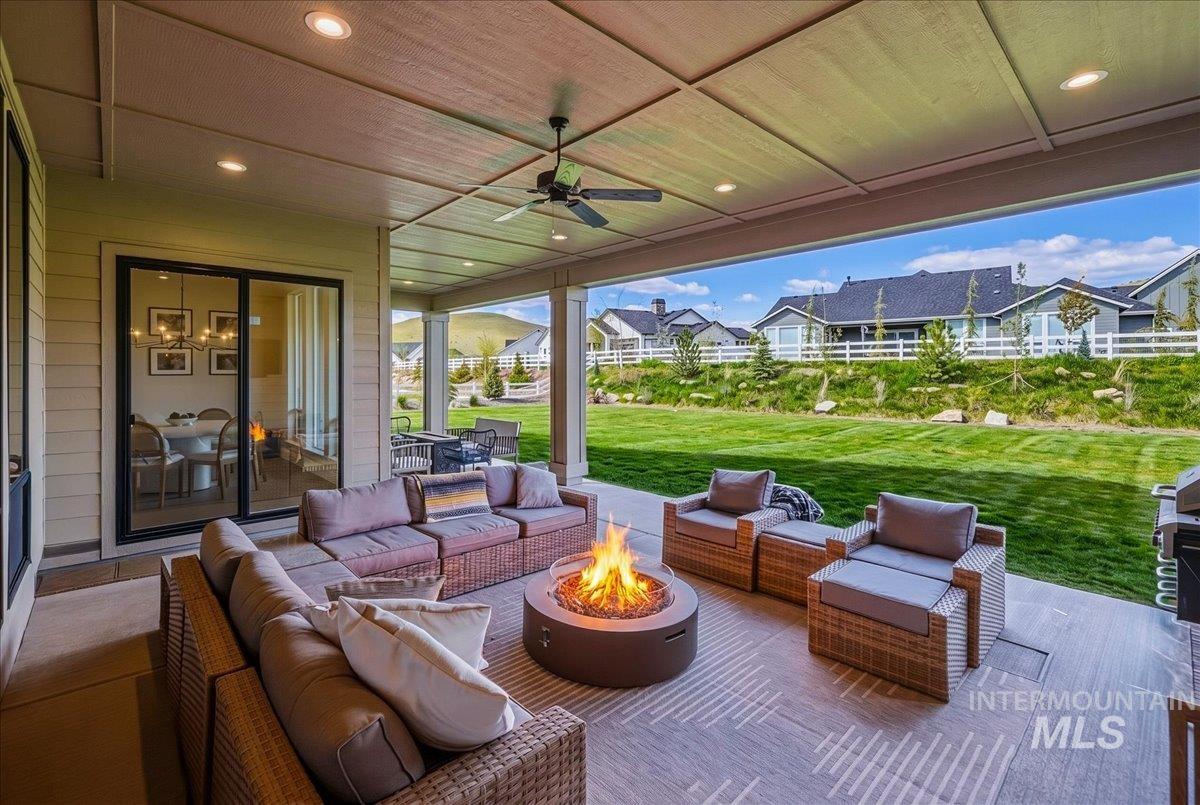 Covered outdoor living space featuring a built-in fire pit, recessed lighting, and a ceiling fan