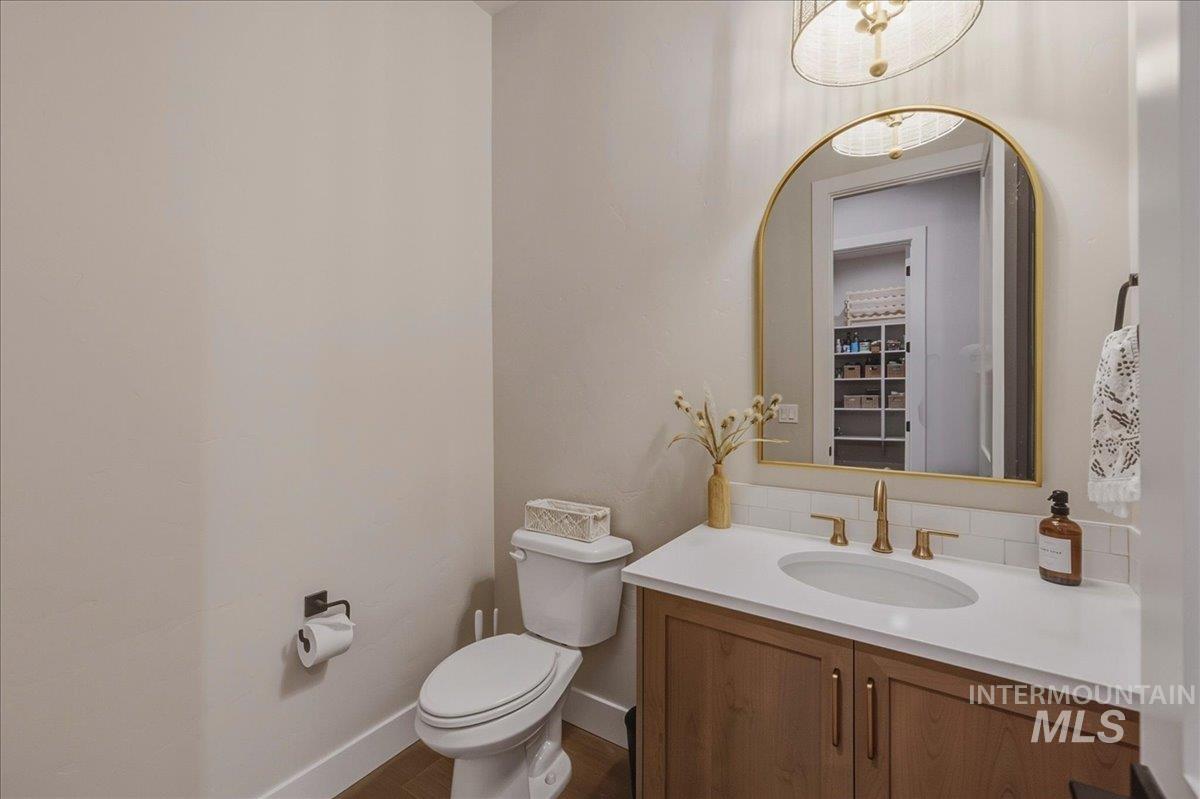 Powder room featuring a wood-finish vanity with a white countertop and gold-toned hardware