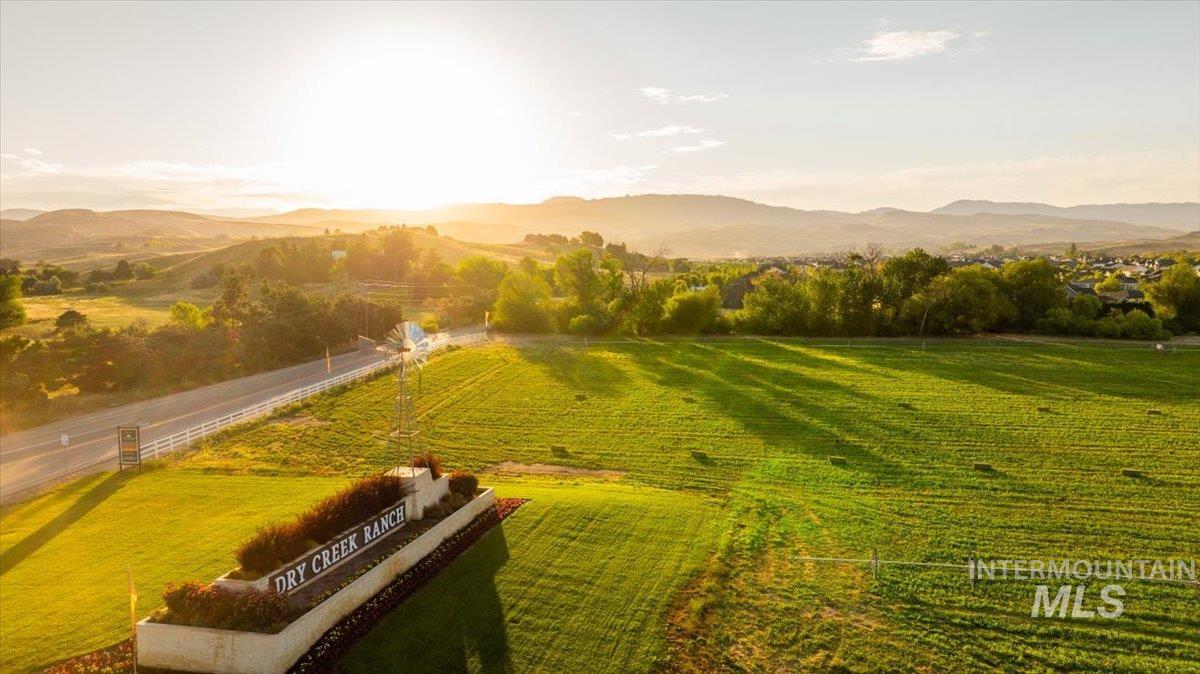 Expansive green fields with distant mountains and a community sign