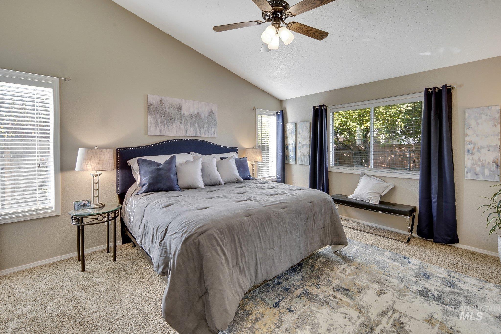 Bedroom with vaulted ceiling, carpet floors, ceiling fan, and a textured ceiling