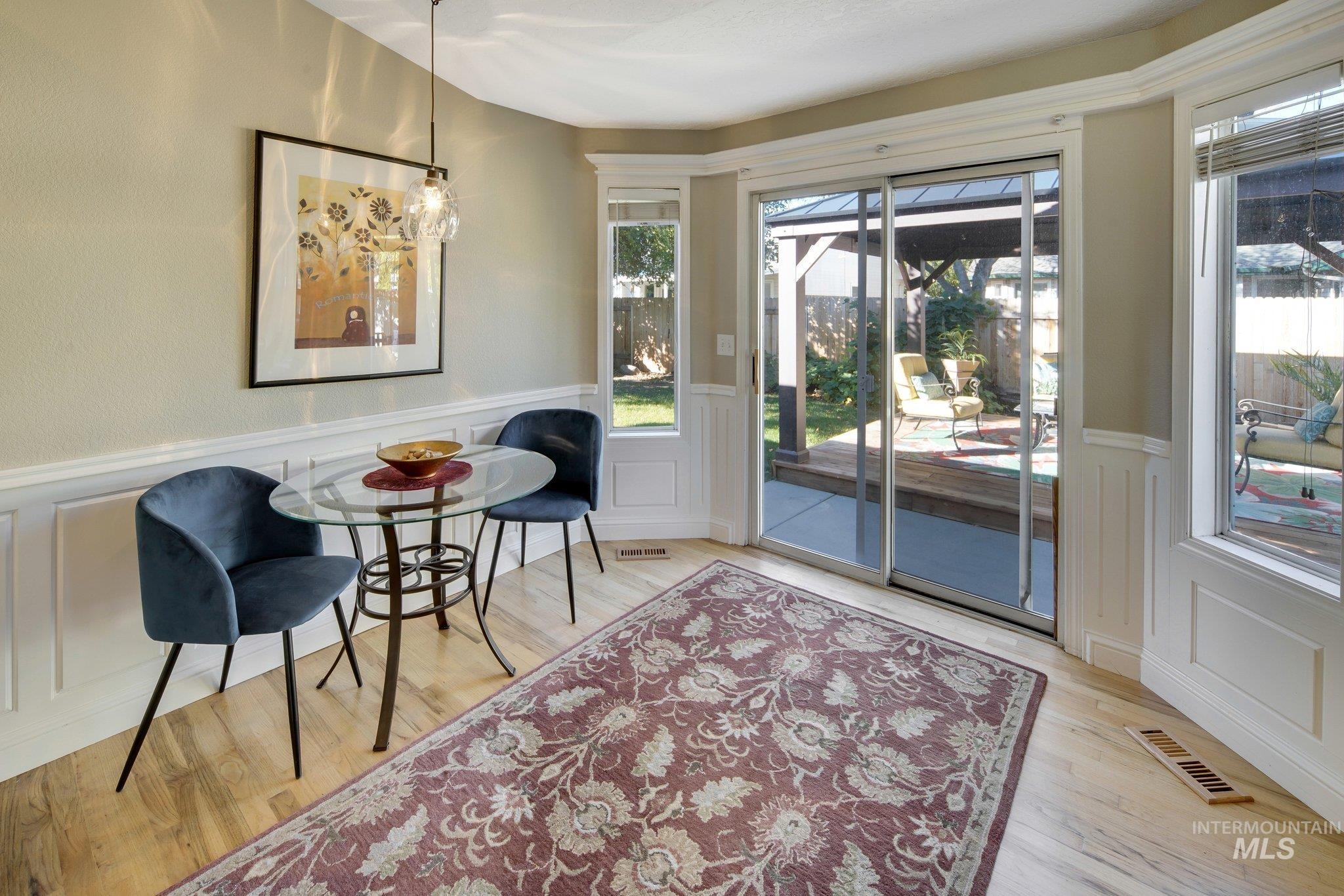 Living area with a decorative wall, a wainscoted wall, and light wood-style floors