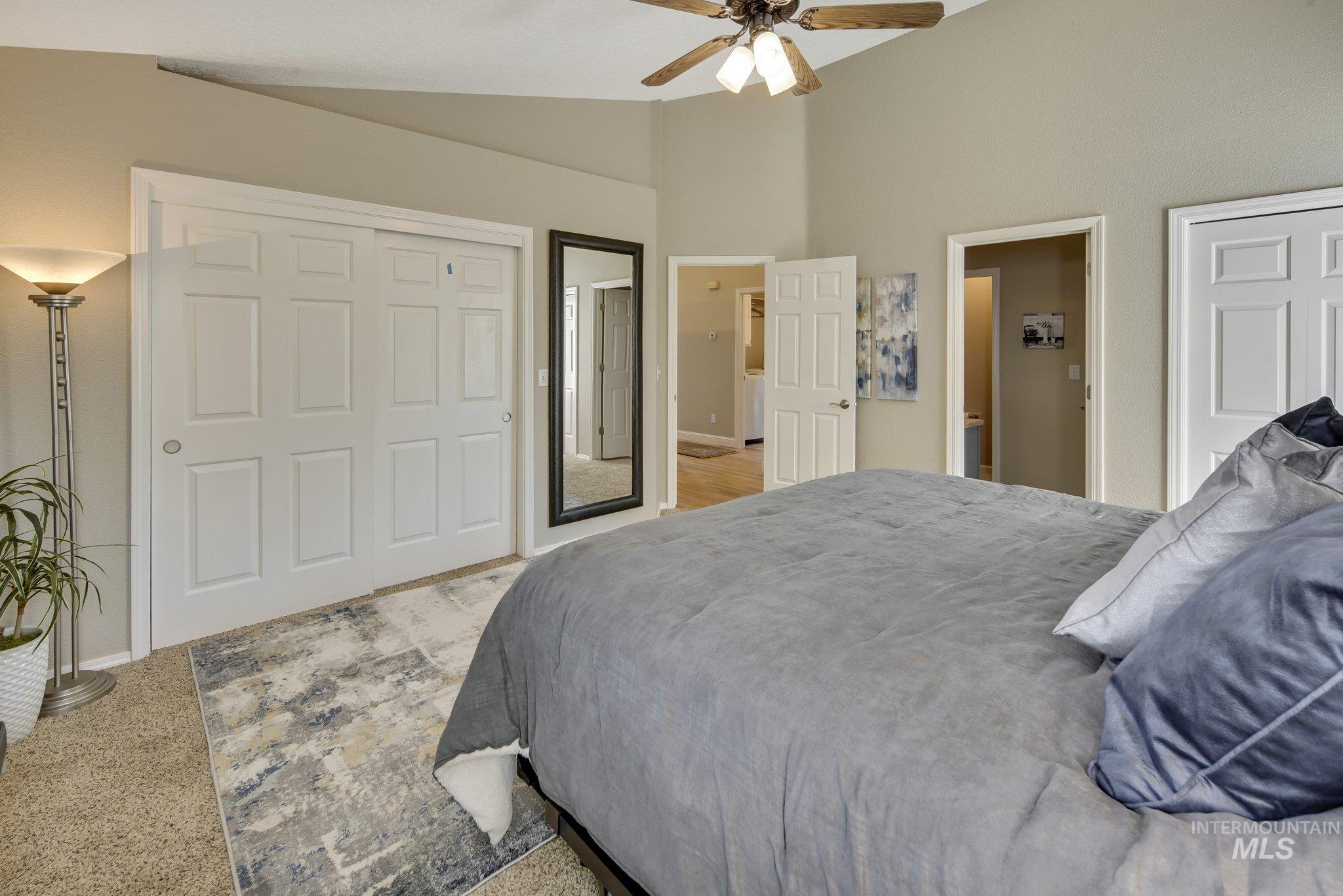Bedroom with high vaulted ceiling, ceiling fan, a closet, and light carpet
