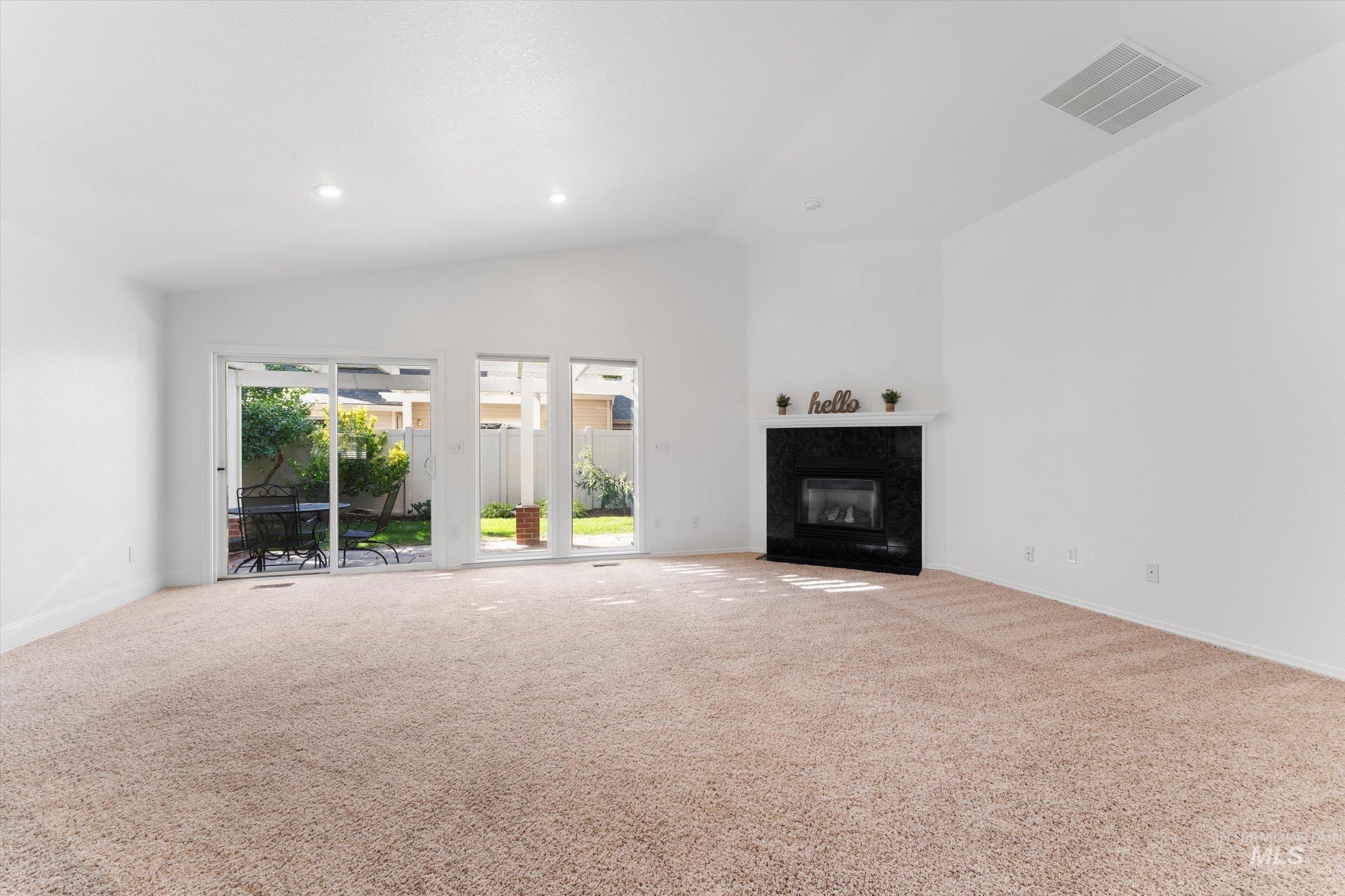 Unfurnished living room with carpet, a high end fireplace, recessed lighting, and high vaulted ceiling