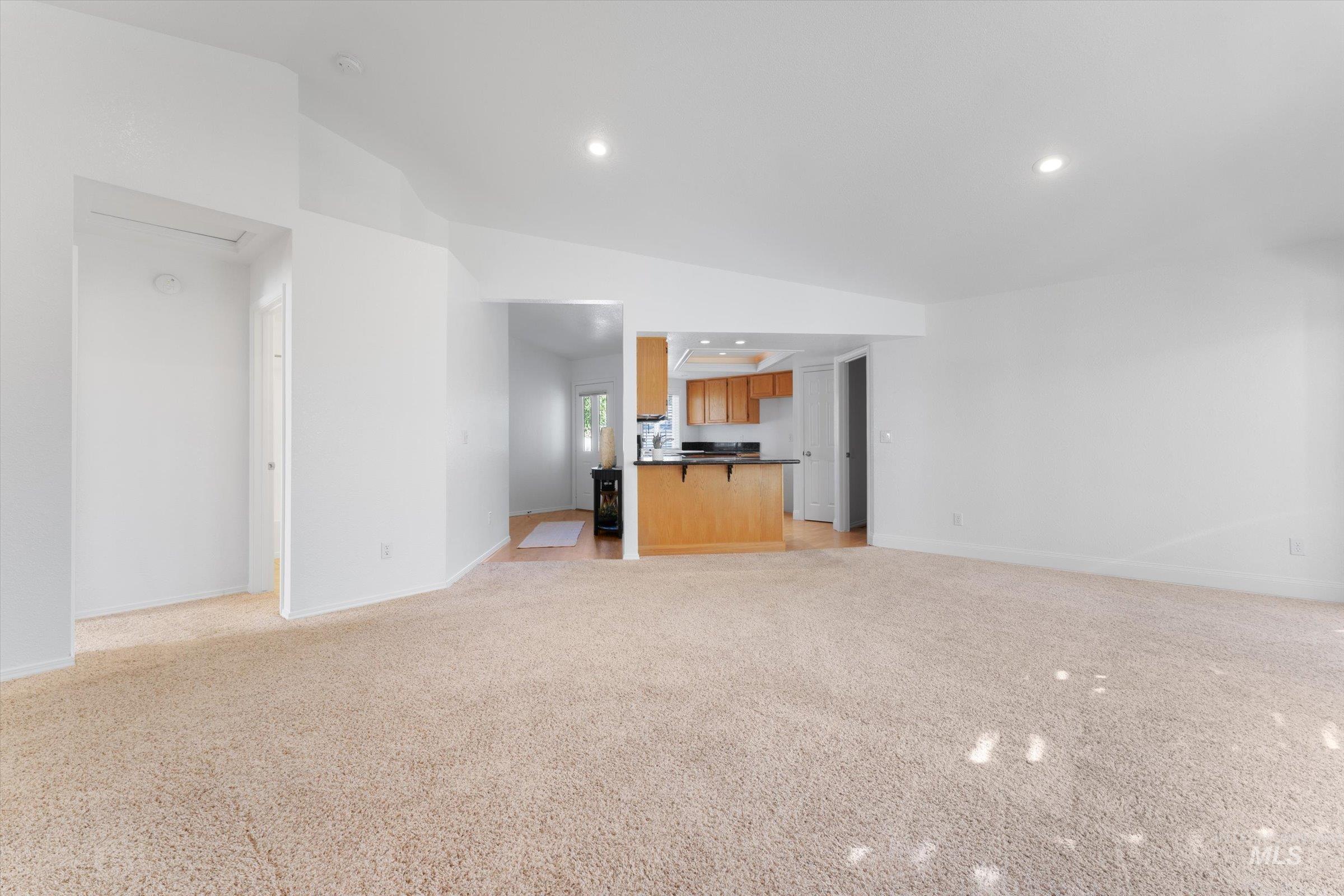 Unfurnished living room with recessed lighting, vaulted ceiling, and light colored carpet
