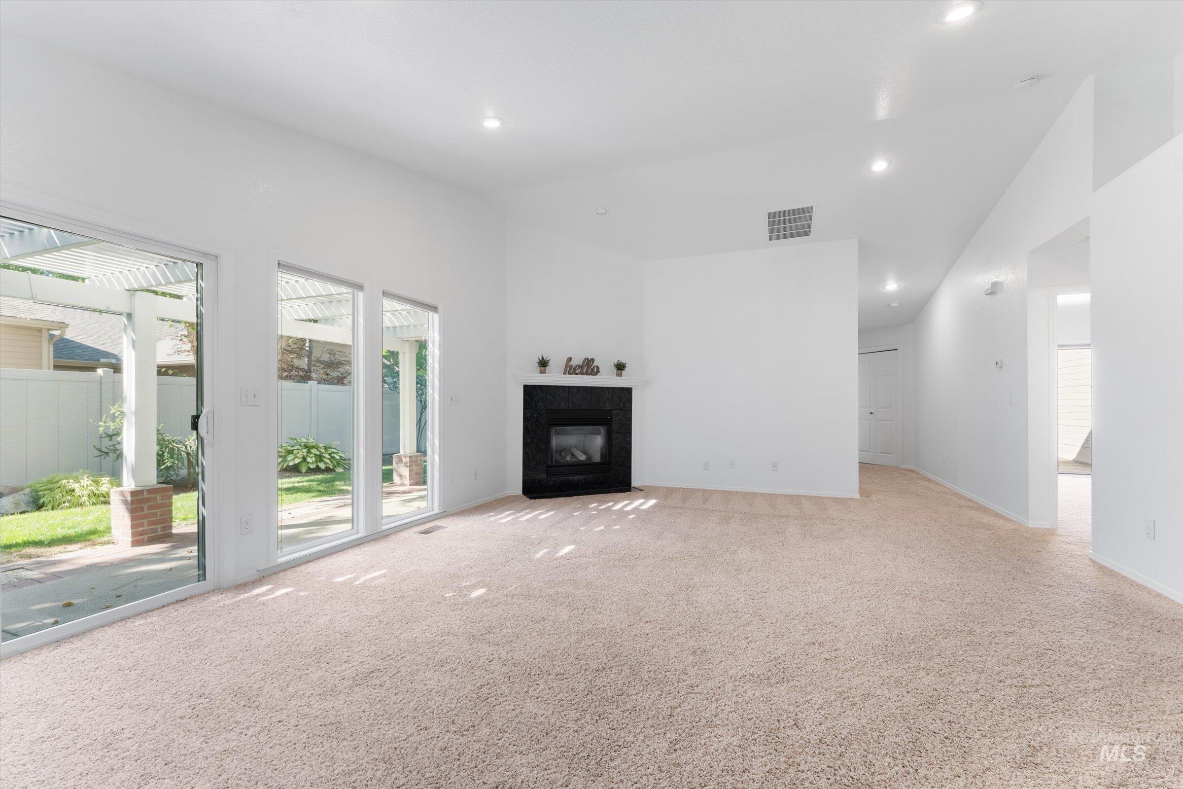 Unfurnished living room featuring carpet floors, a premium fireplace, high vaulted ceiling, and recessed lighting