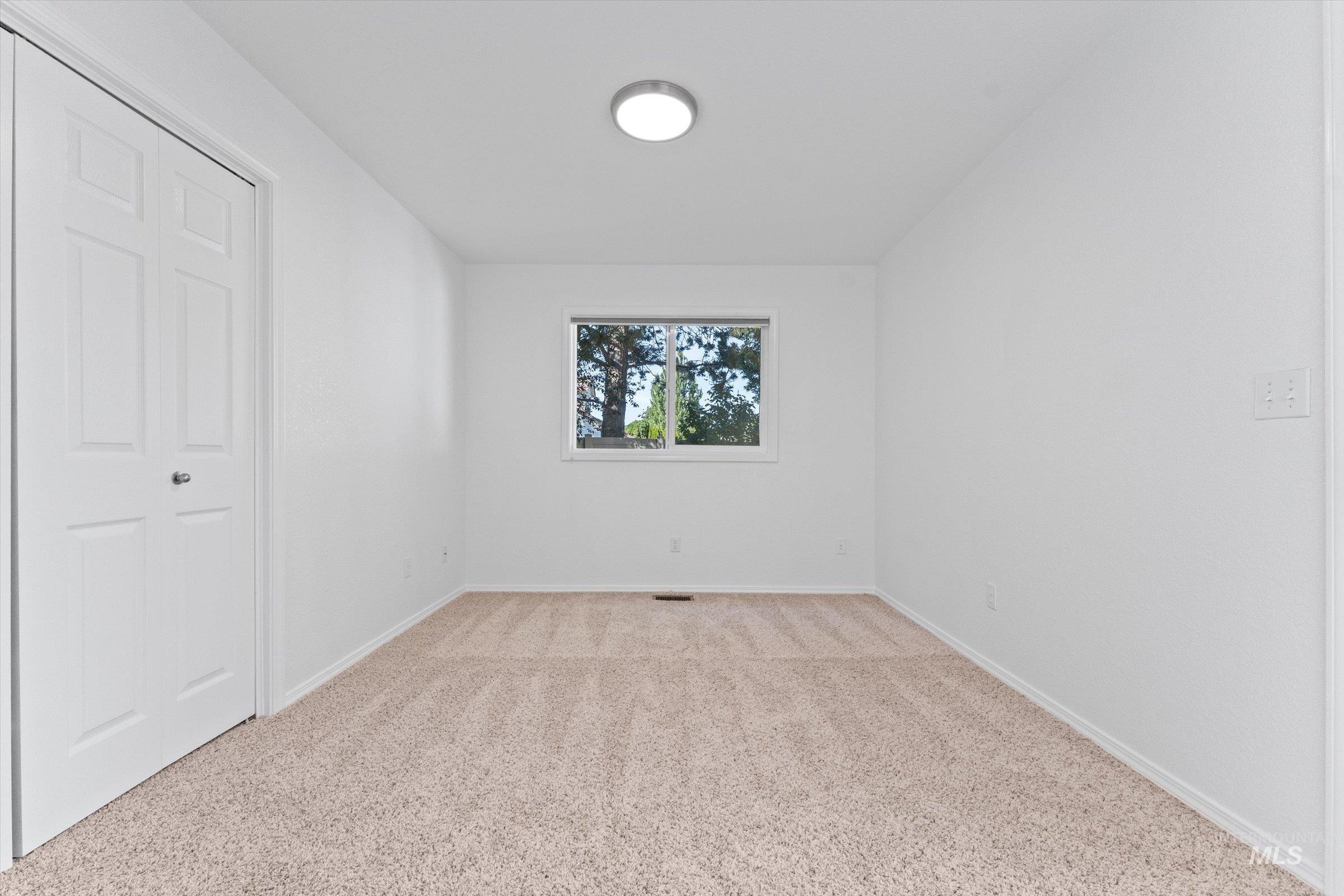 Unfurnished bedroom with light carpet and baseboards