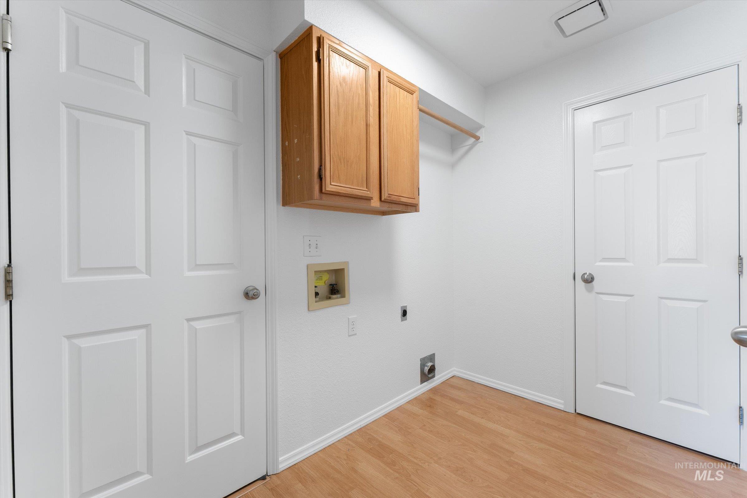 Laundry room featuring hookup for an electric dryer, light wood-style floors, cabinet space, and washer hookup
