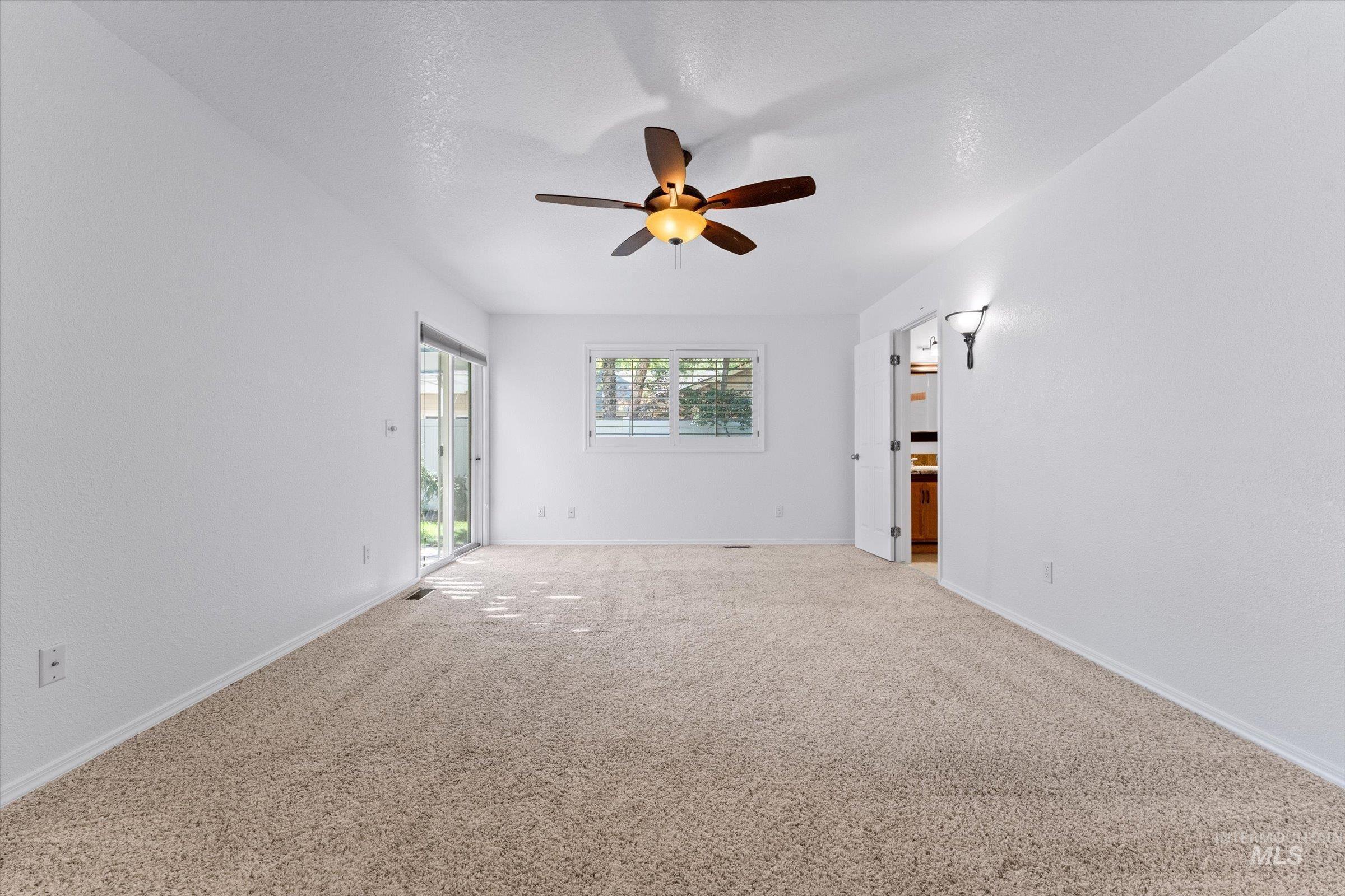 Unfurnished living room with carpet and ceiling fan