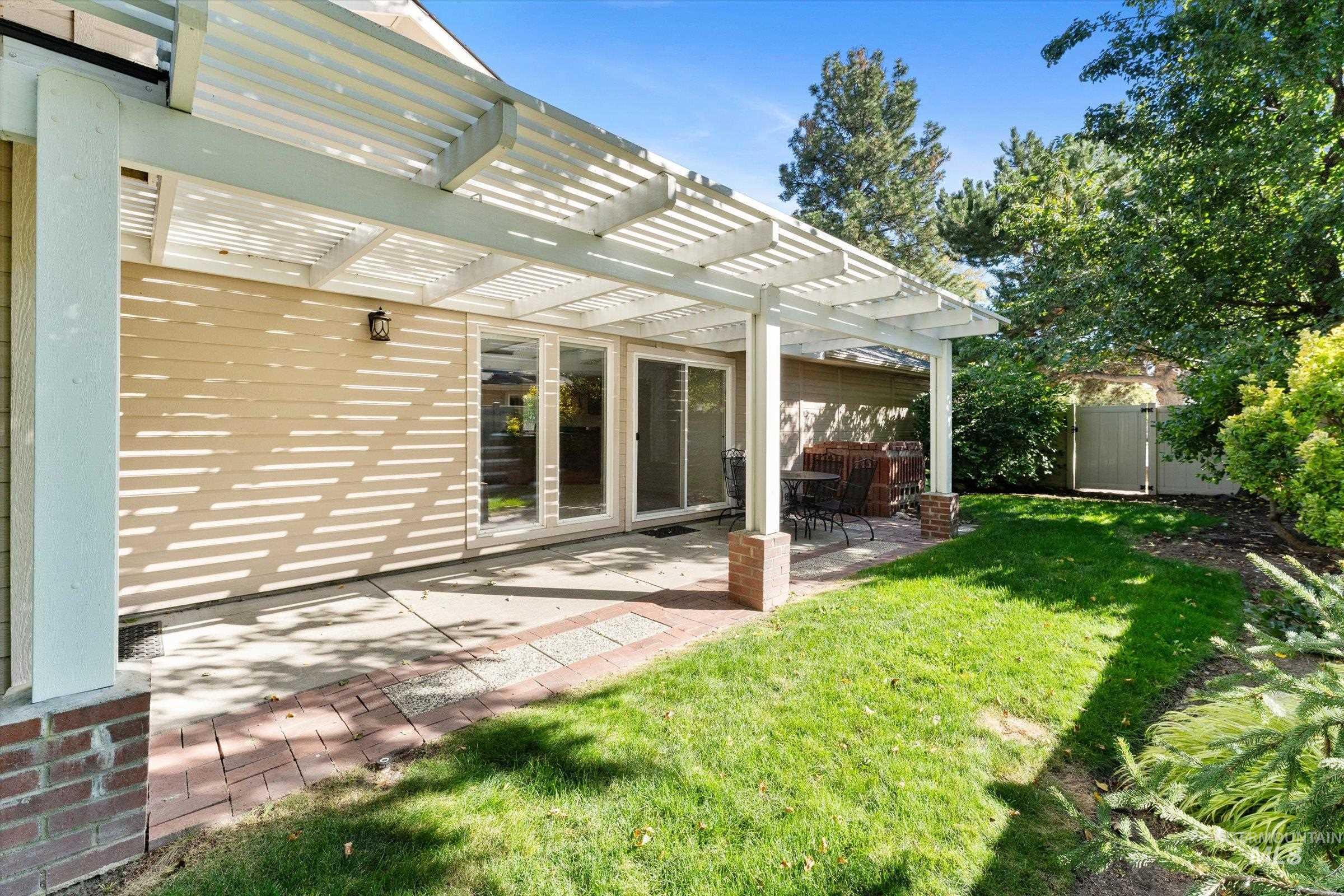 View of green lawn with a pergola and a patio