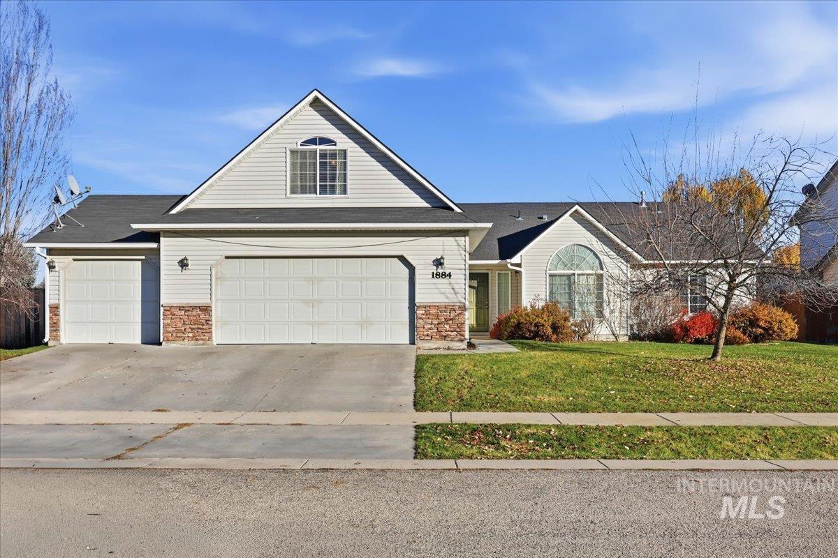 Traditional home featuring a front yard, driveway, stone siding, and an attached garage