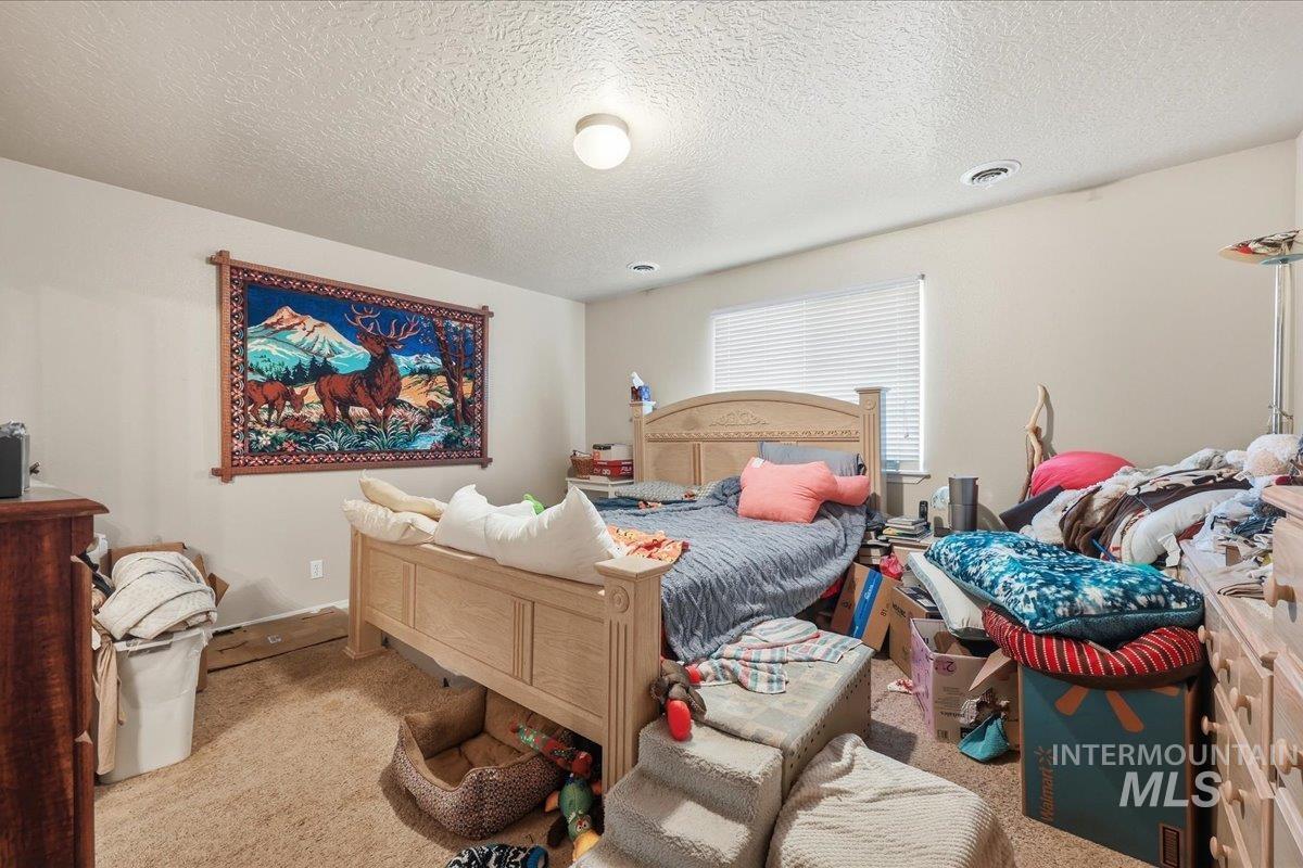 Carpeted bedroom with a textured ceiling and baseboards