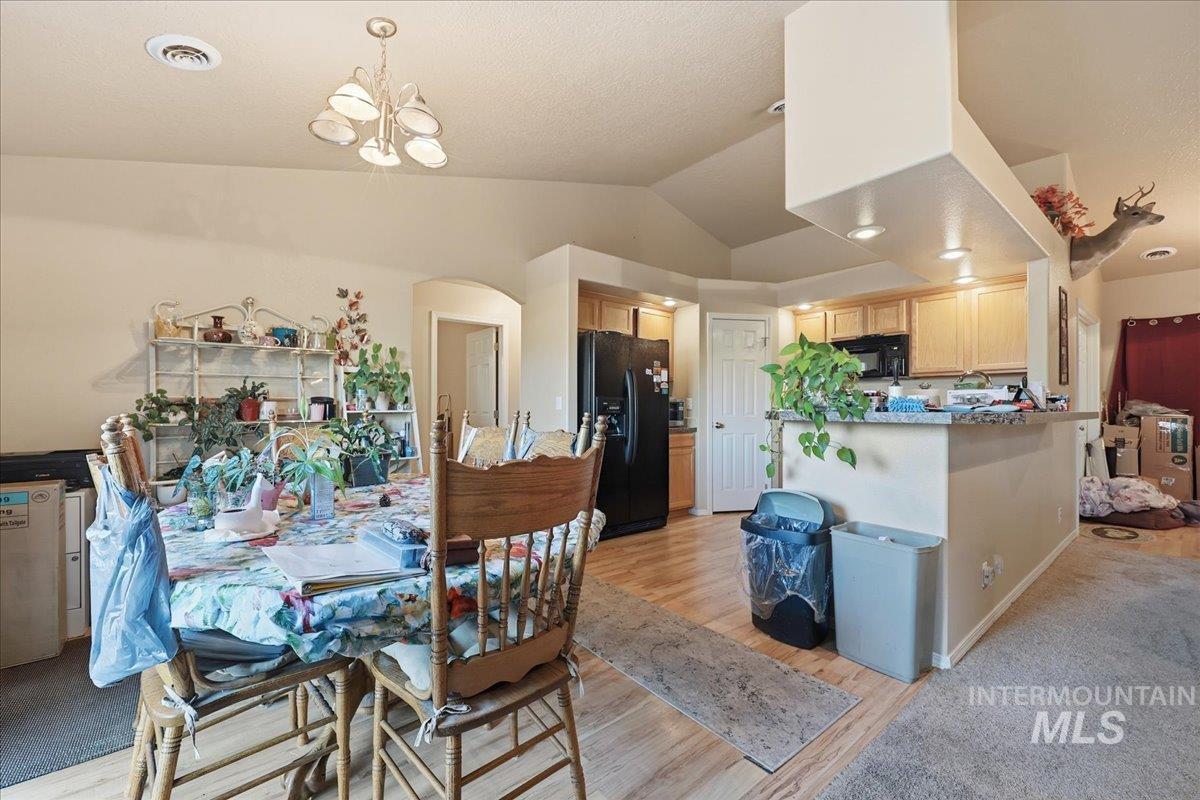 Dining area with light wood-style flooring, lofted ceiling, and arched walkways