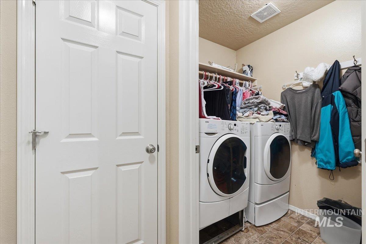Laundry room with a textured ceiling and washing machine and dryer
