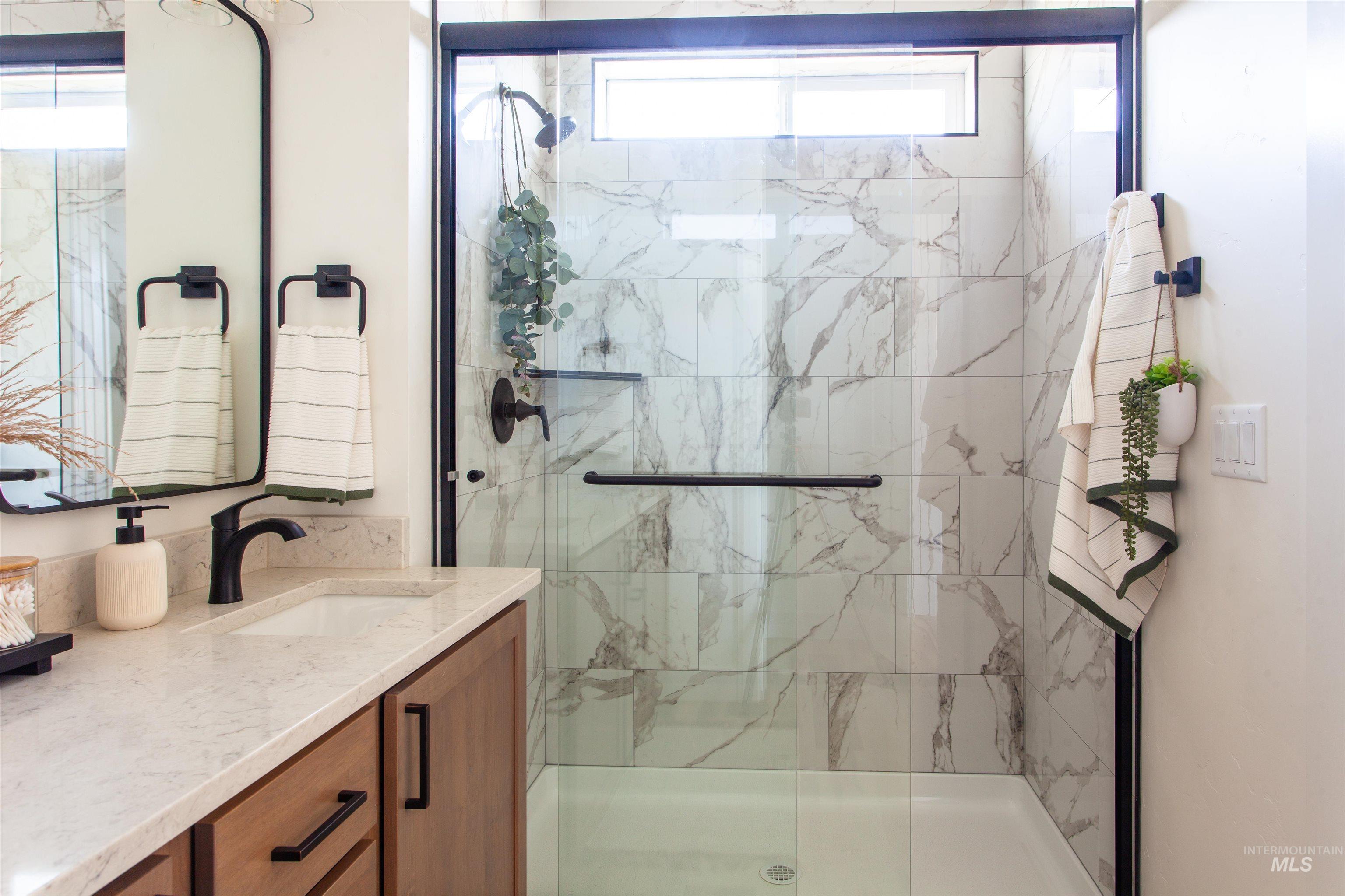 Bathroom with vanity and a marble finish shower