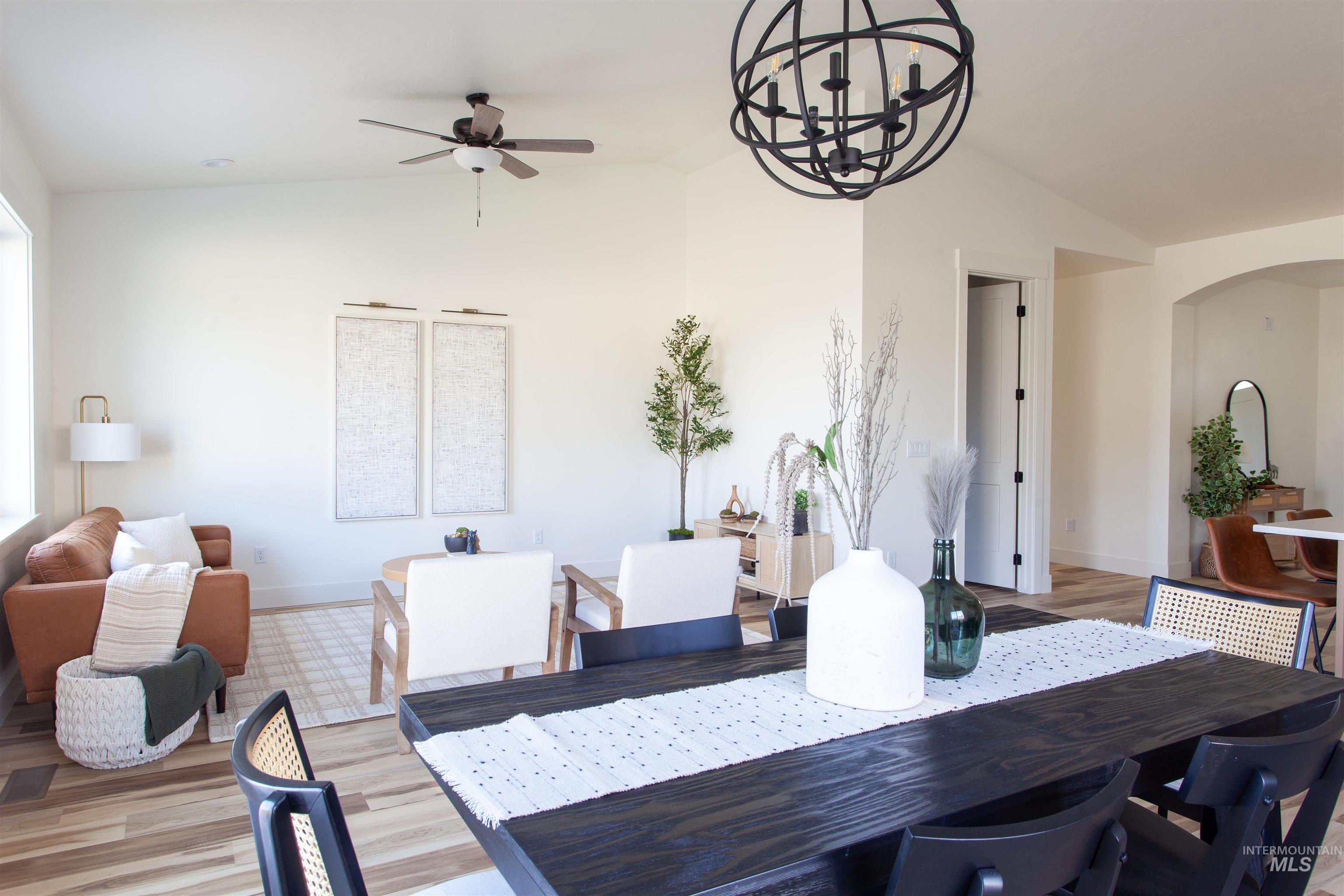 Dining area with vaulted ceiling, light wood-type flooring, ceiling fan, a chandelier, and arched walkways