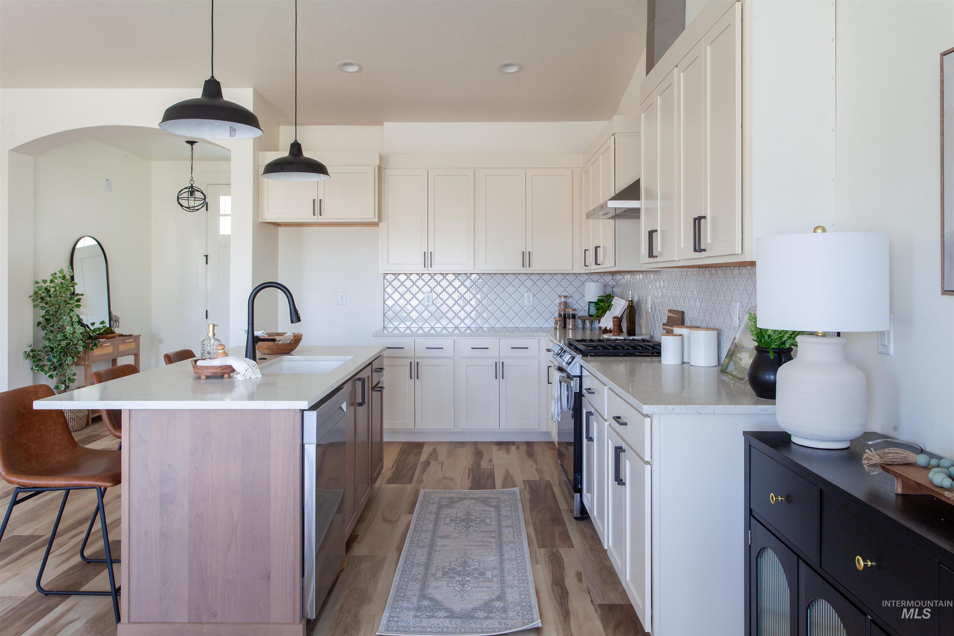 Kitchen featuring a breakfast bar area, appliances with stainless steel finishes, tasteful backsplash, white cabinets, and pendant lighting